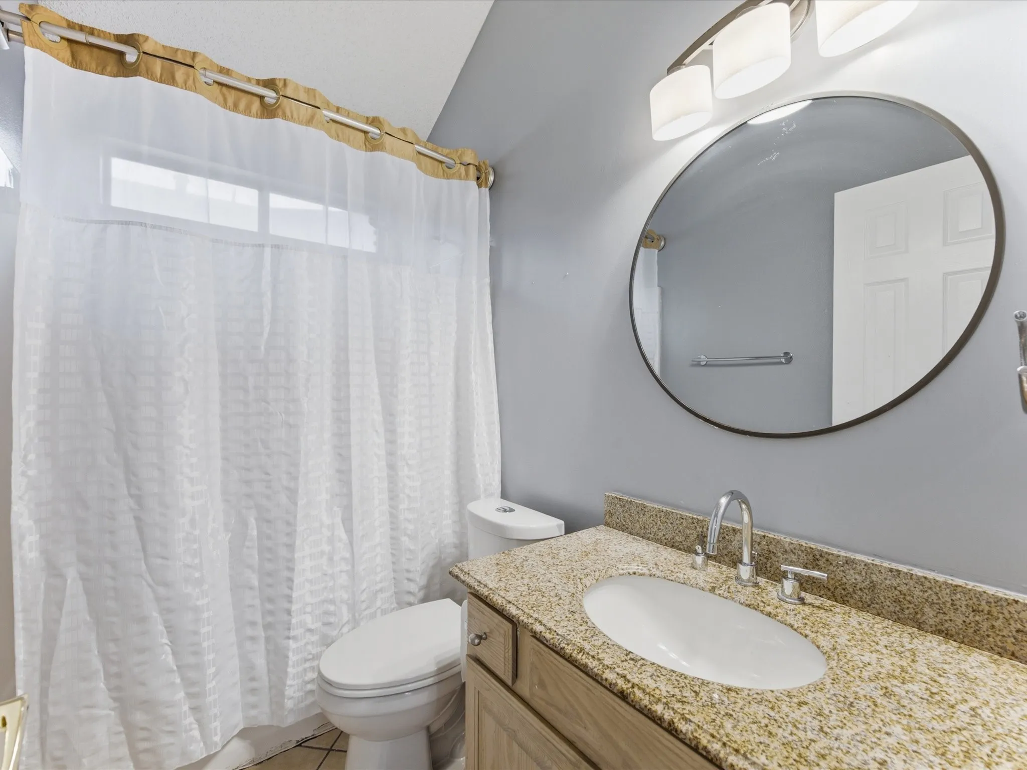 Bathroom featuring a vanity with a granite-finish countertop, undermount sink, and chrome faucet