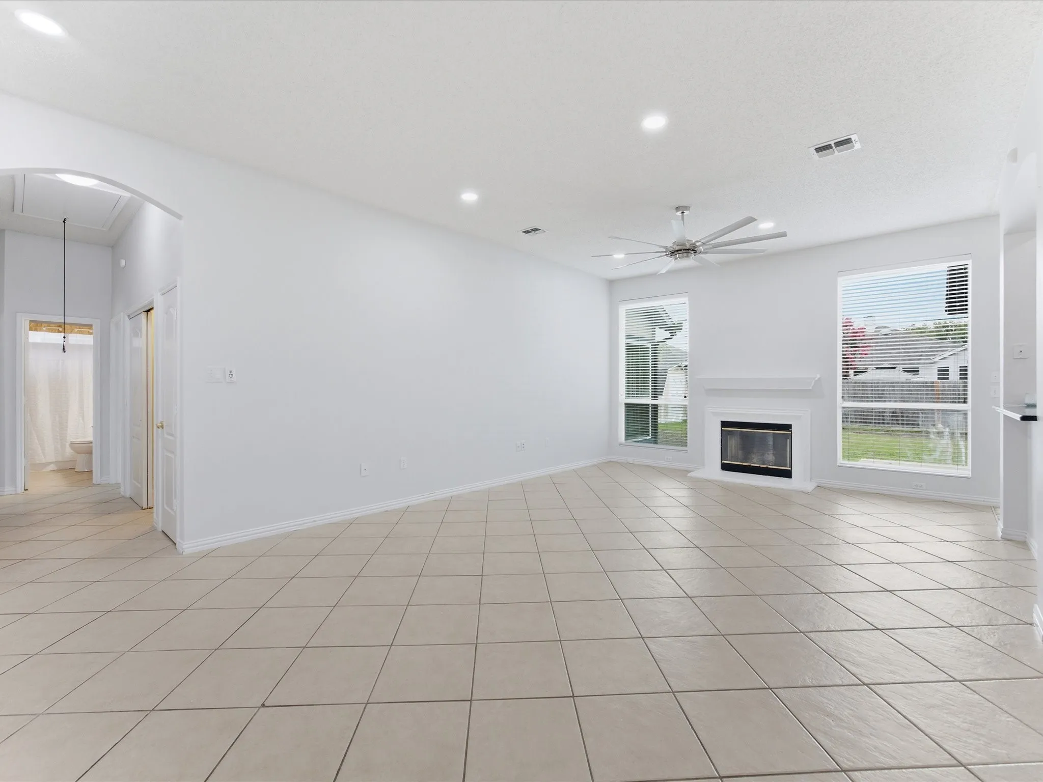 Spacious living area featuring large format tile flooring and a white fireplace with a mantle