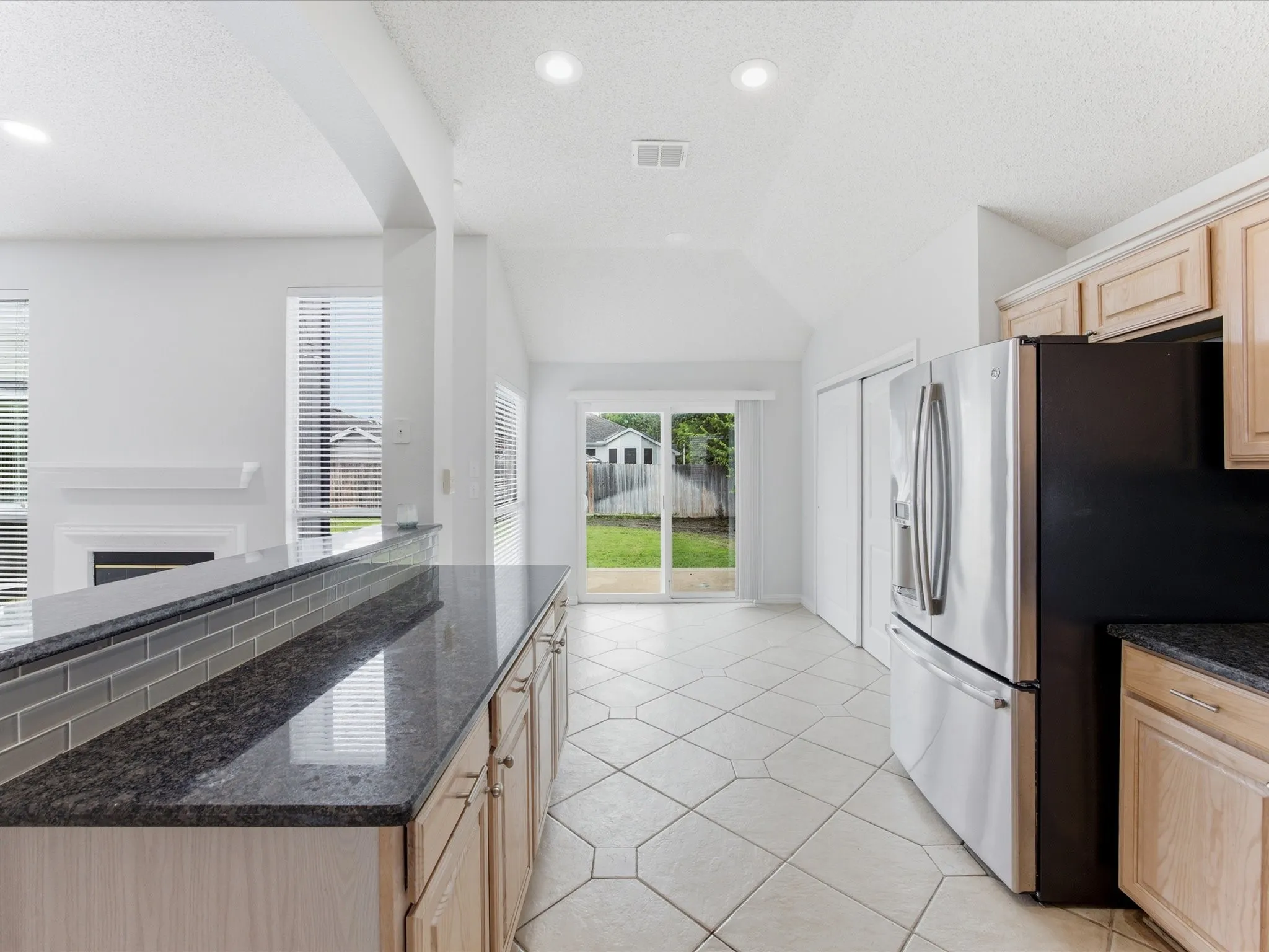 Kitchen featuring granite countertops, wood cabinetry, subway tile backsplash, and tile flooring