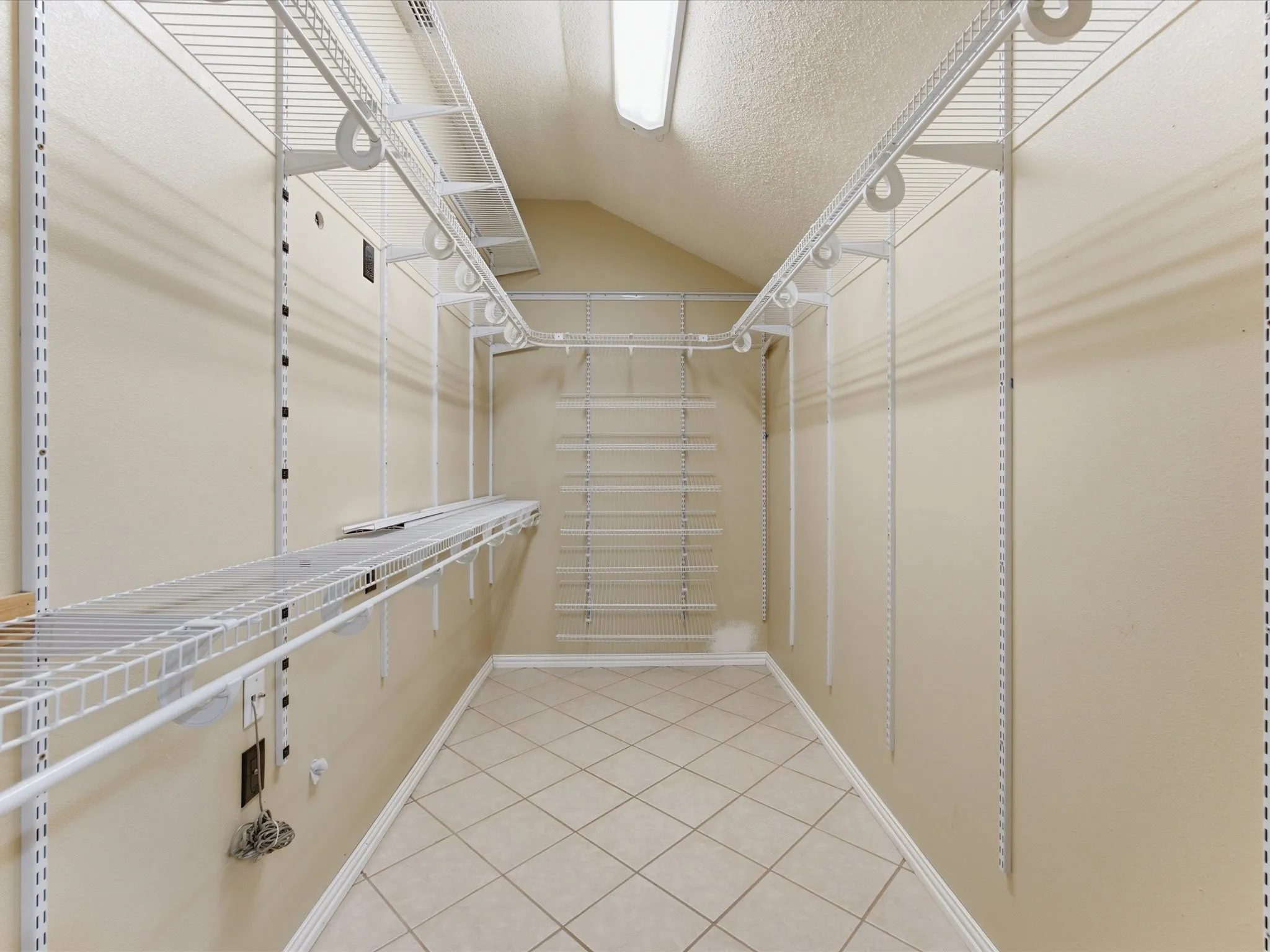Spacious closet featuring an extensive wire shelving system, durable tile flooring, and integrated overhead lighting