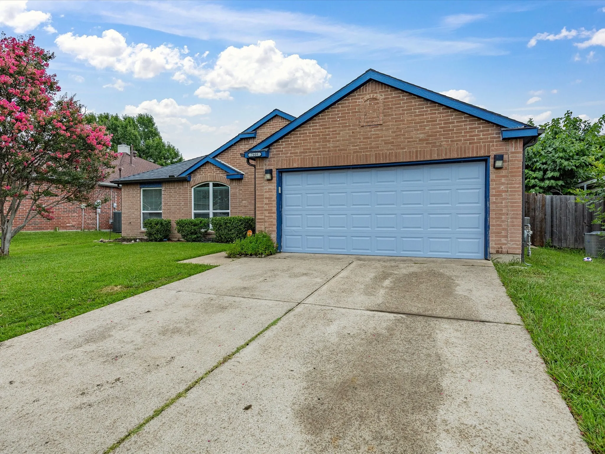 Brick exterior with a light blue garage door, complementing trim, and an arched window