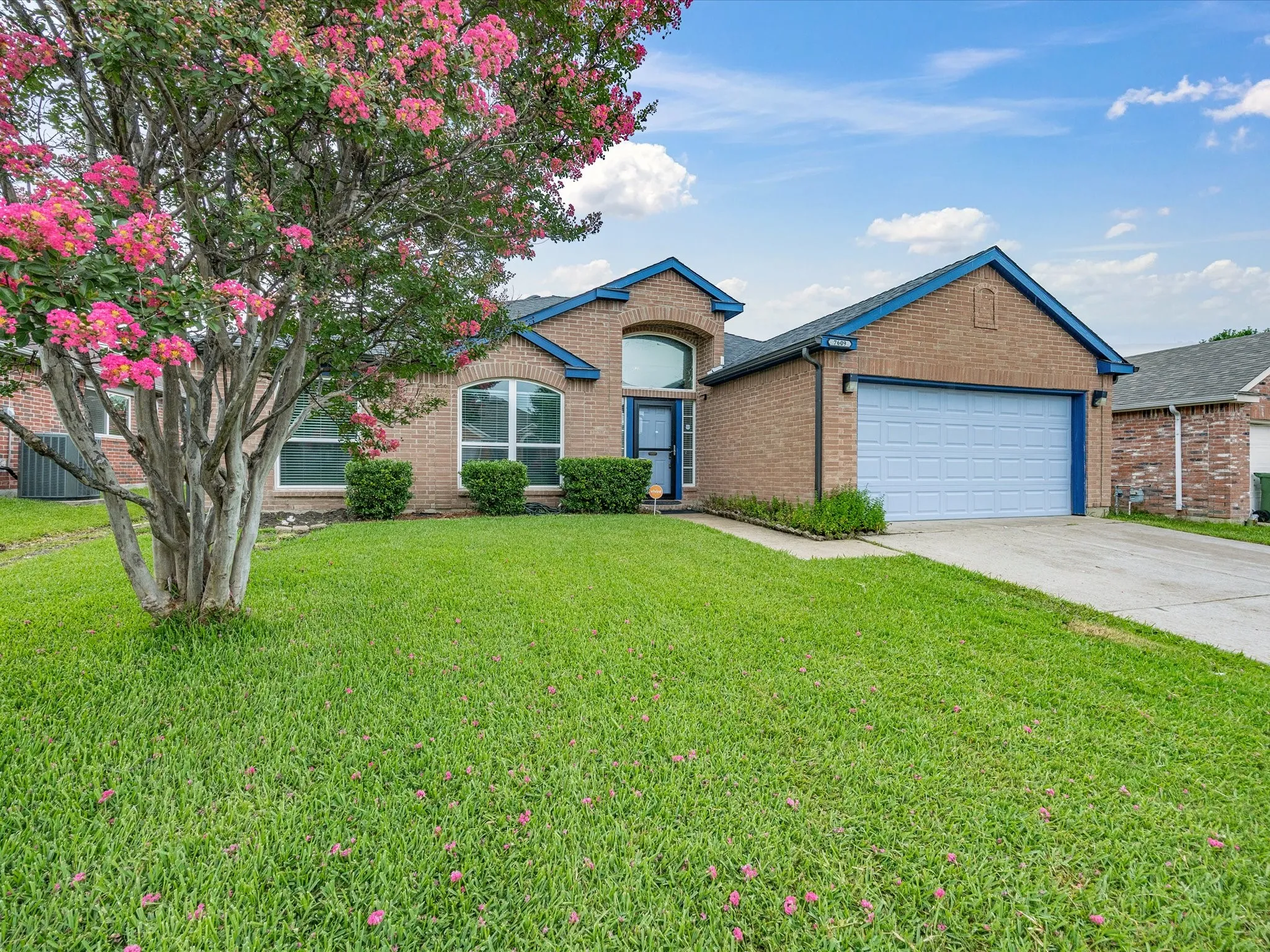 Brick exterior with blue trim accents and a two-car garage