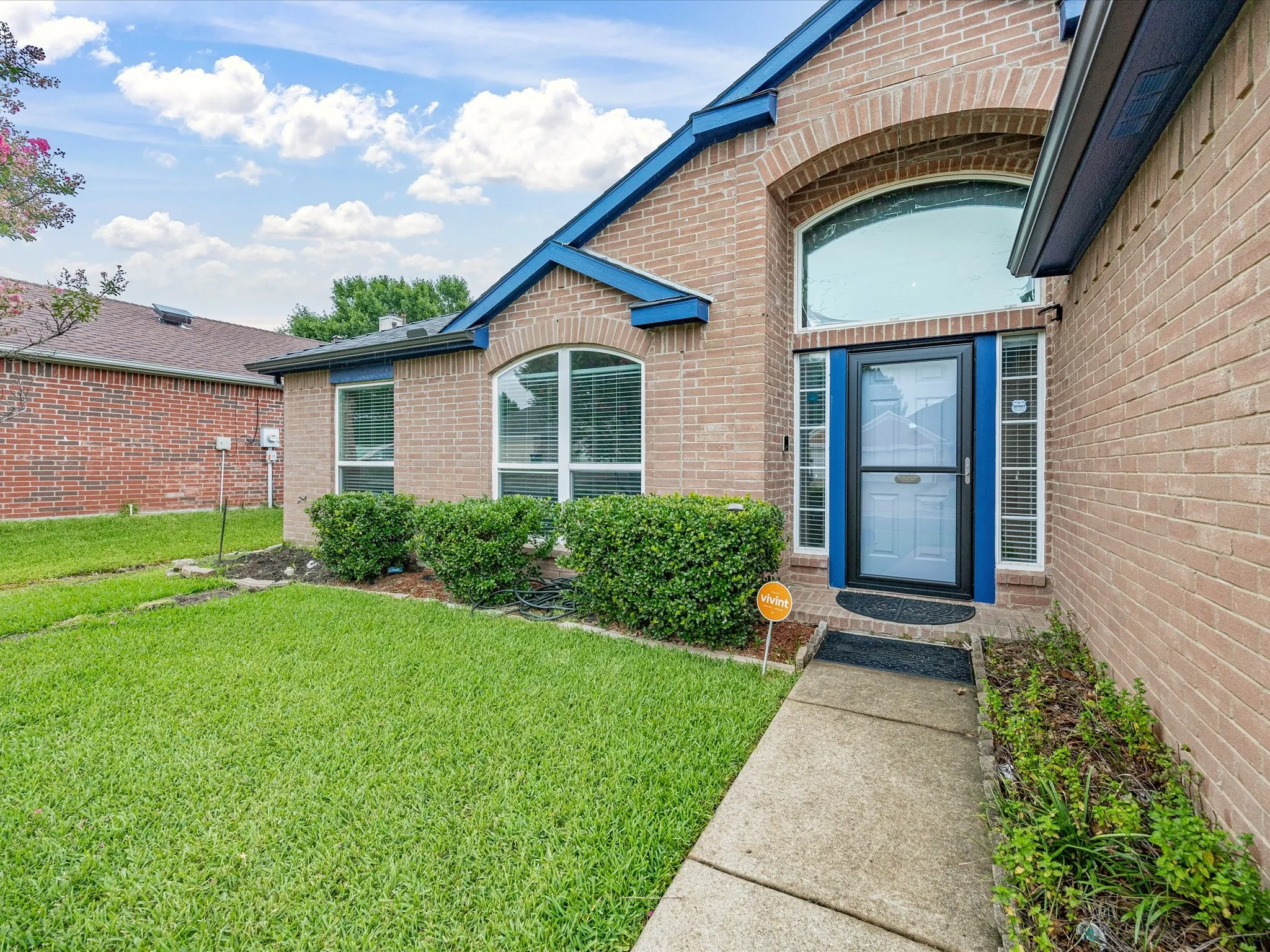 Brick exterior featuring a prominent arched window above the entry, a storm door, and contrasting blue trim accents