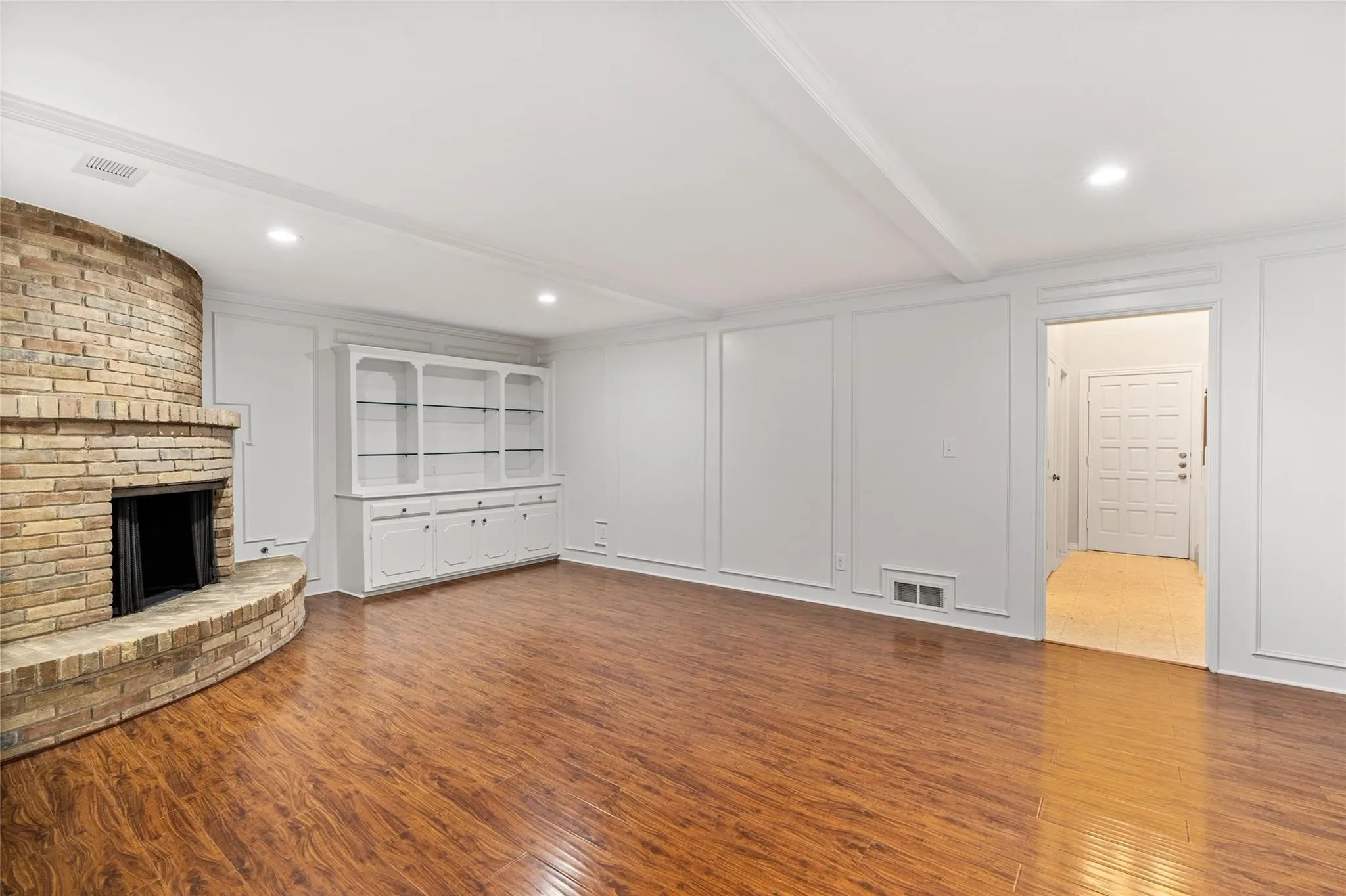 Large living room with built-in storage, gleaming floors and neutral paint.