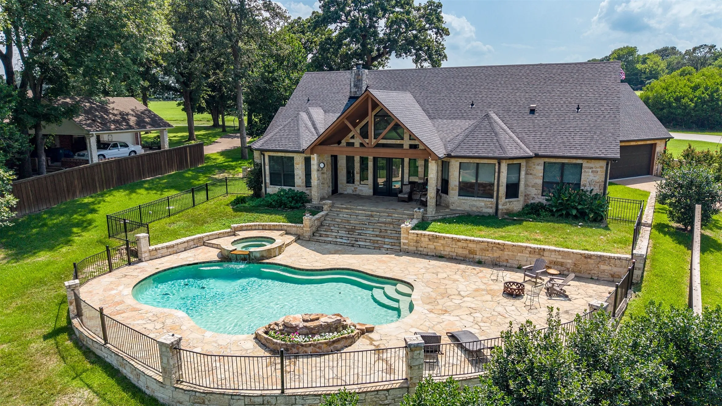 Backyard oasis featuring a freeform swimming pool, integrated spa, and expansive stone patio