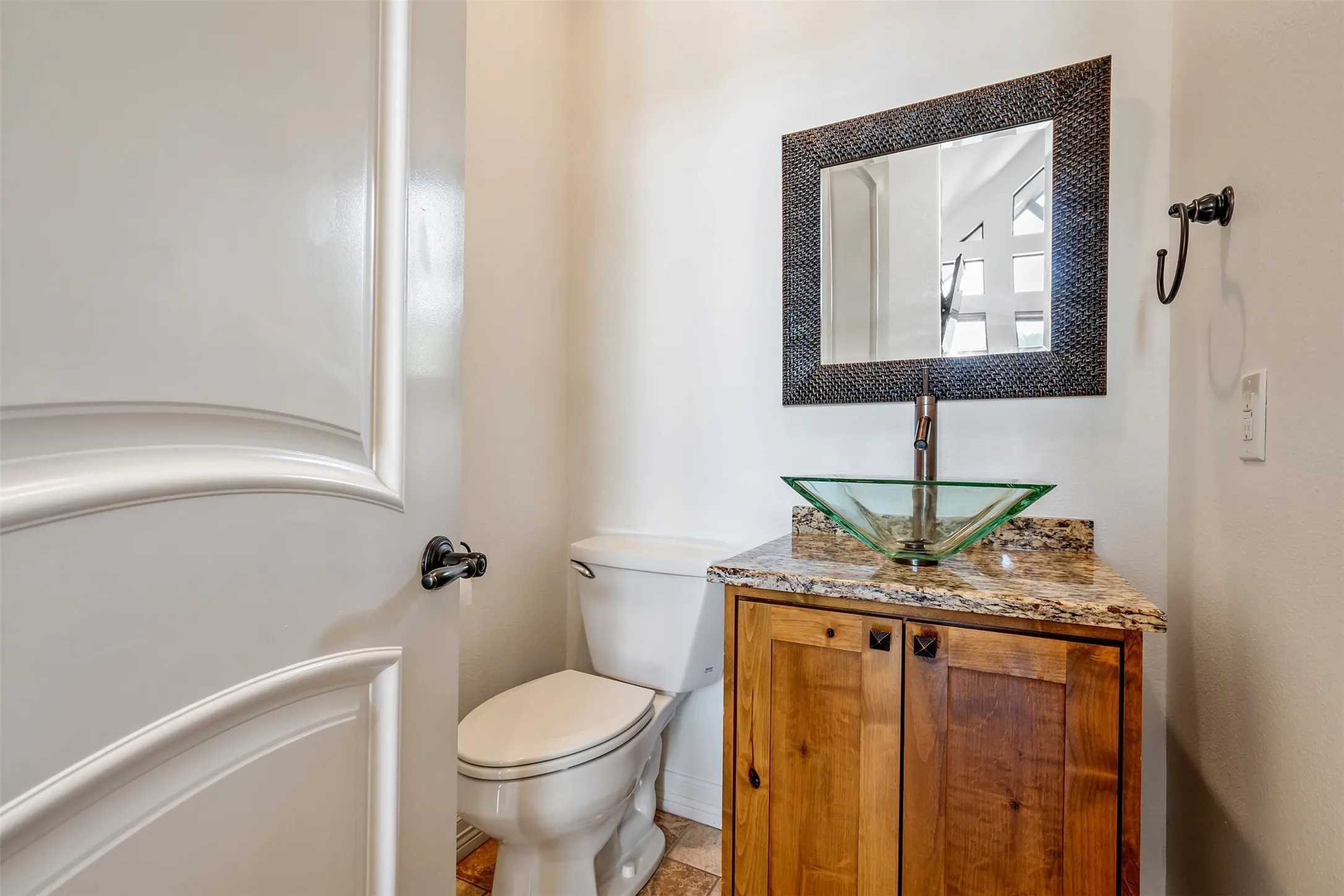 Bathroom featuring a natural wood-finish vanity with a granite countertop and a glass vessel sink