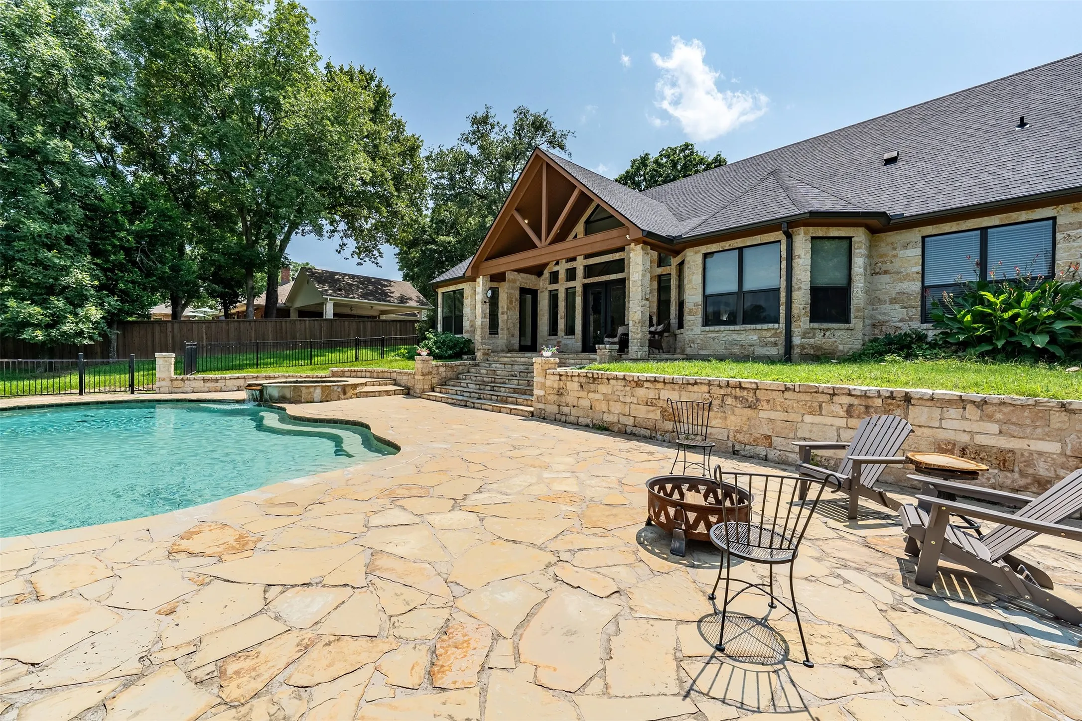 Expansive flagstone patio surrounding a freeform swimming pool with an integrated spa