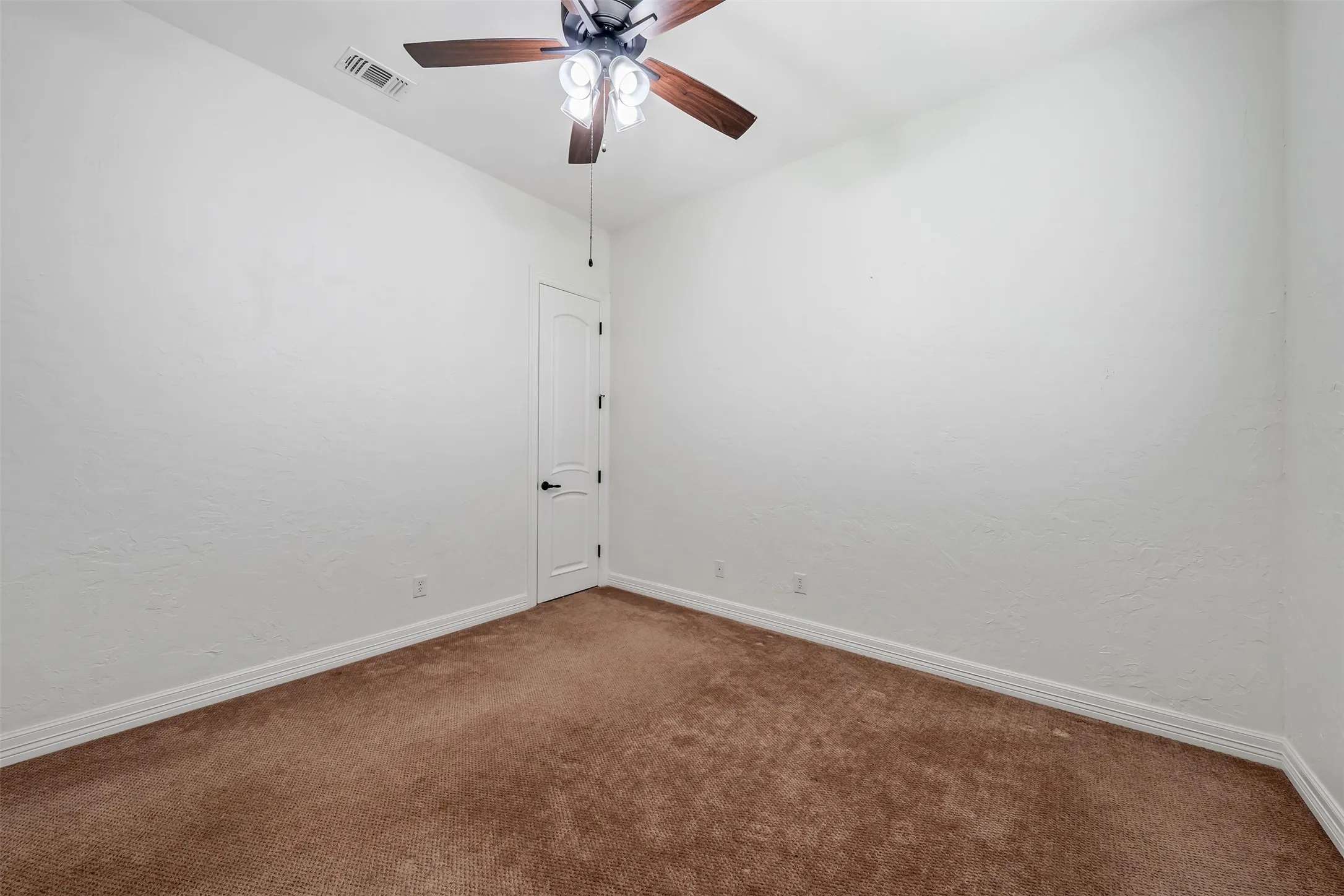 Neutral-toned room featuring a ceiling fan with integrated lighting, textured white walls, white trim, and brown carpet flooring