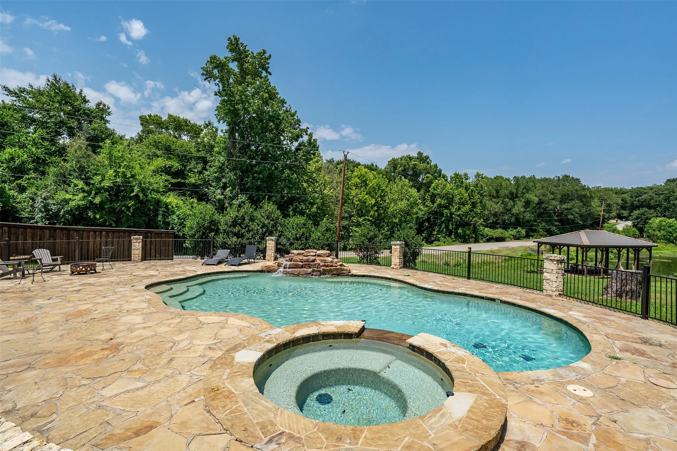 Freeform swimming pool with integrated spa and stone waterfall feature