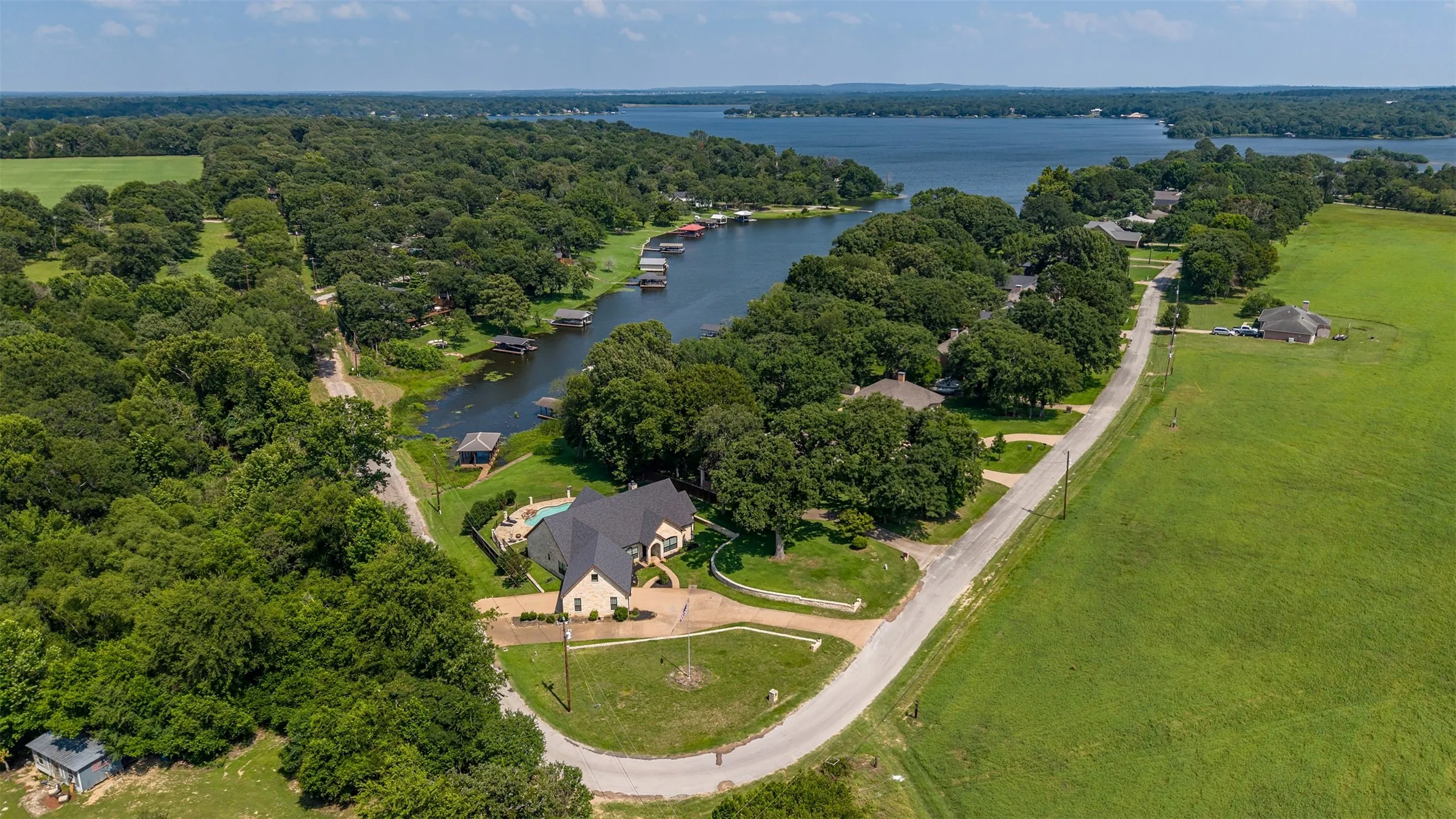 Expansive lakefront property featuring a private boat dock, inground swimming pool, and mature tree coverage