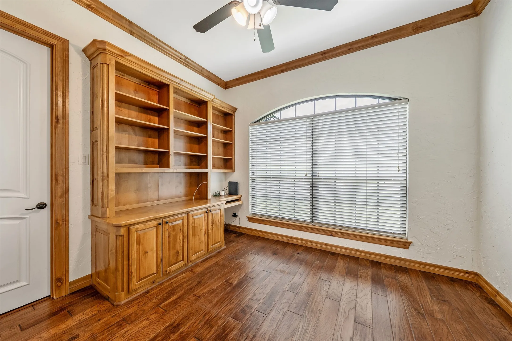 Built-in wood cabinetry featuring open shelving and closed storage, complemented by rich wood-finish flooring