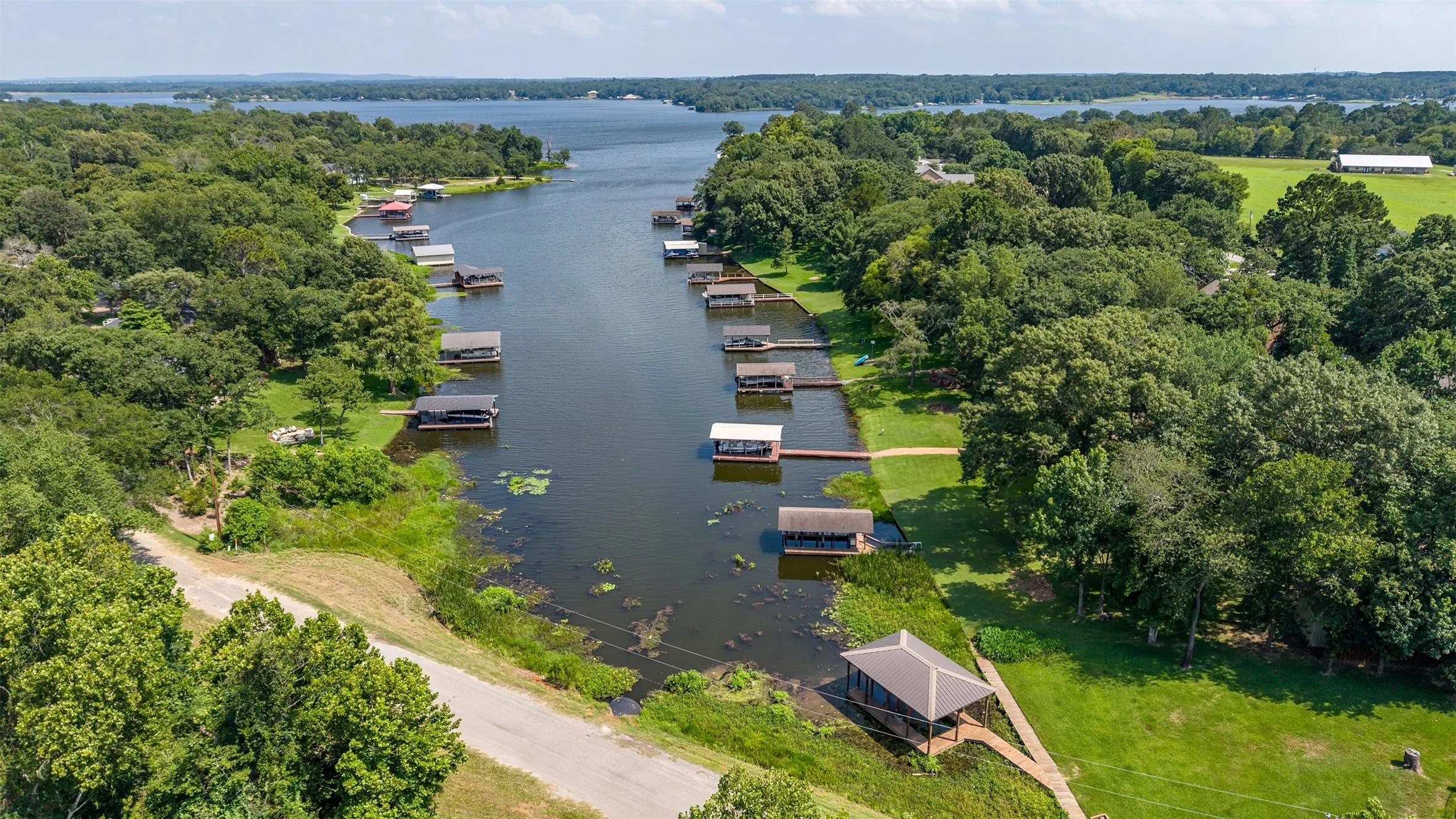 Waterfront canal property featuring multiple boat docks, extensive green space, and mature trees