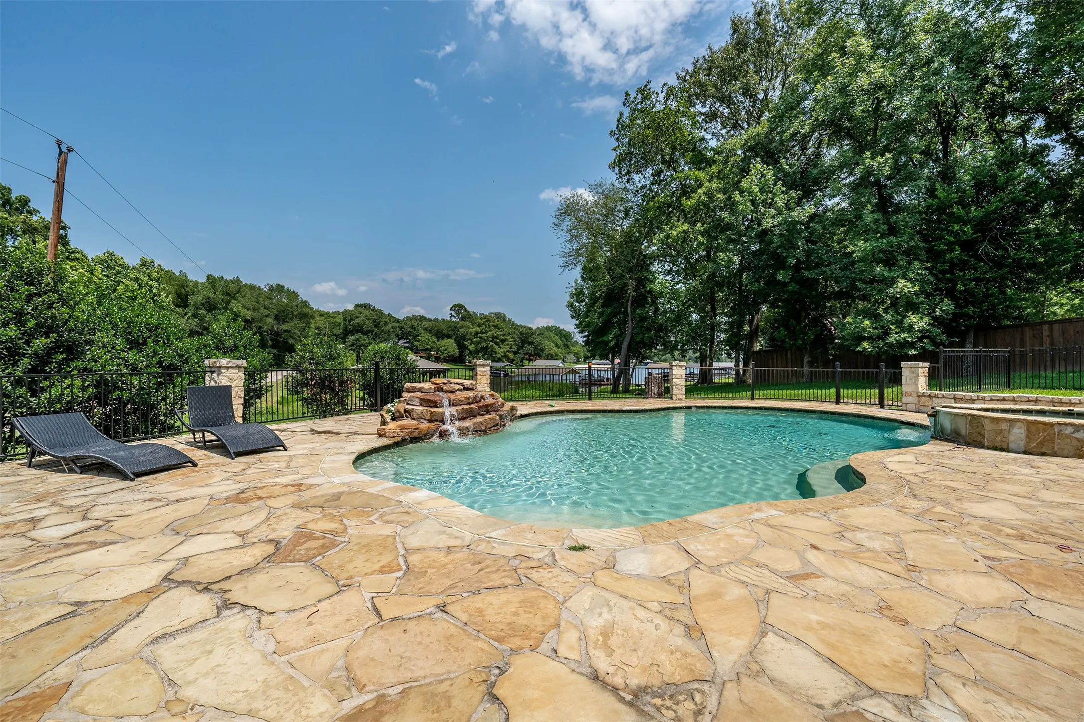 Freeform swimming pool with rock waterfall feature, flagstone patio, and integrated spa