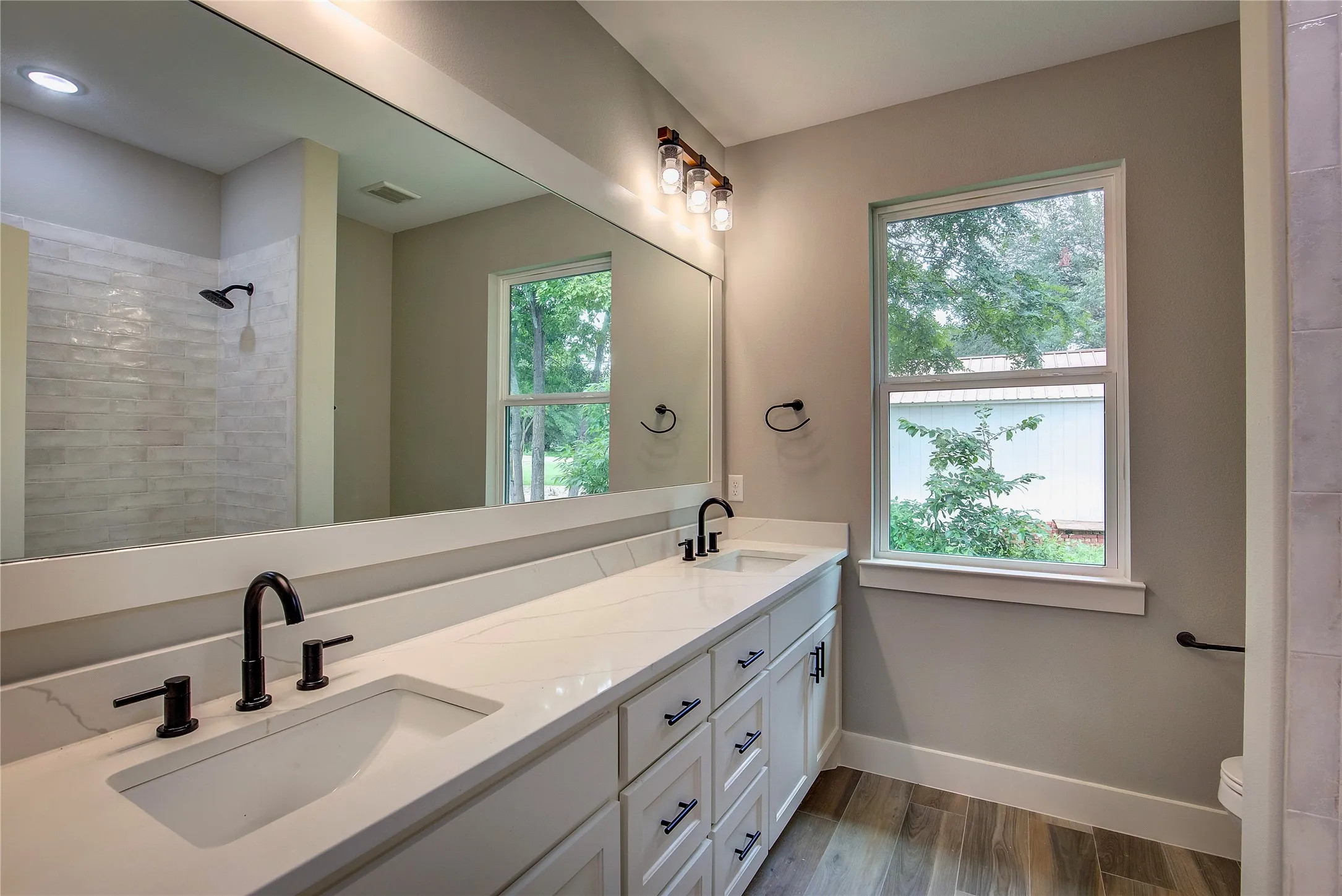 Bathroom with dual vanity, toilet, and wood-type flooring