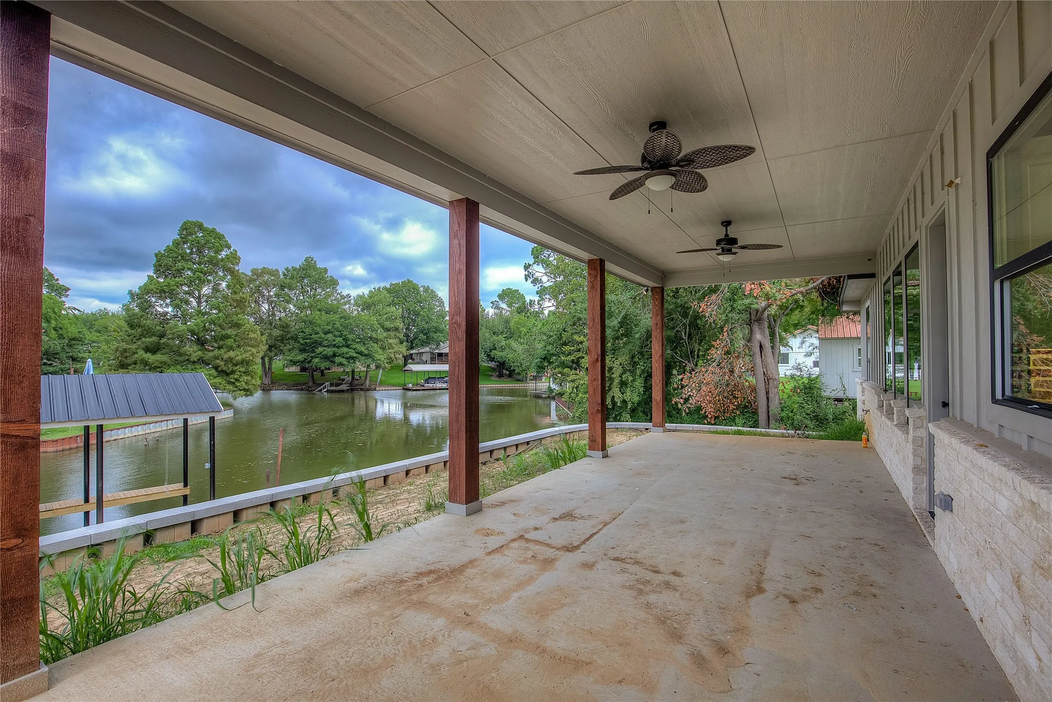 View of patio with a water view, ceiling fan, and a dock