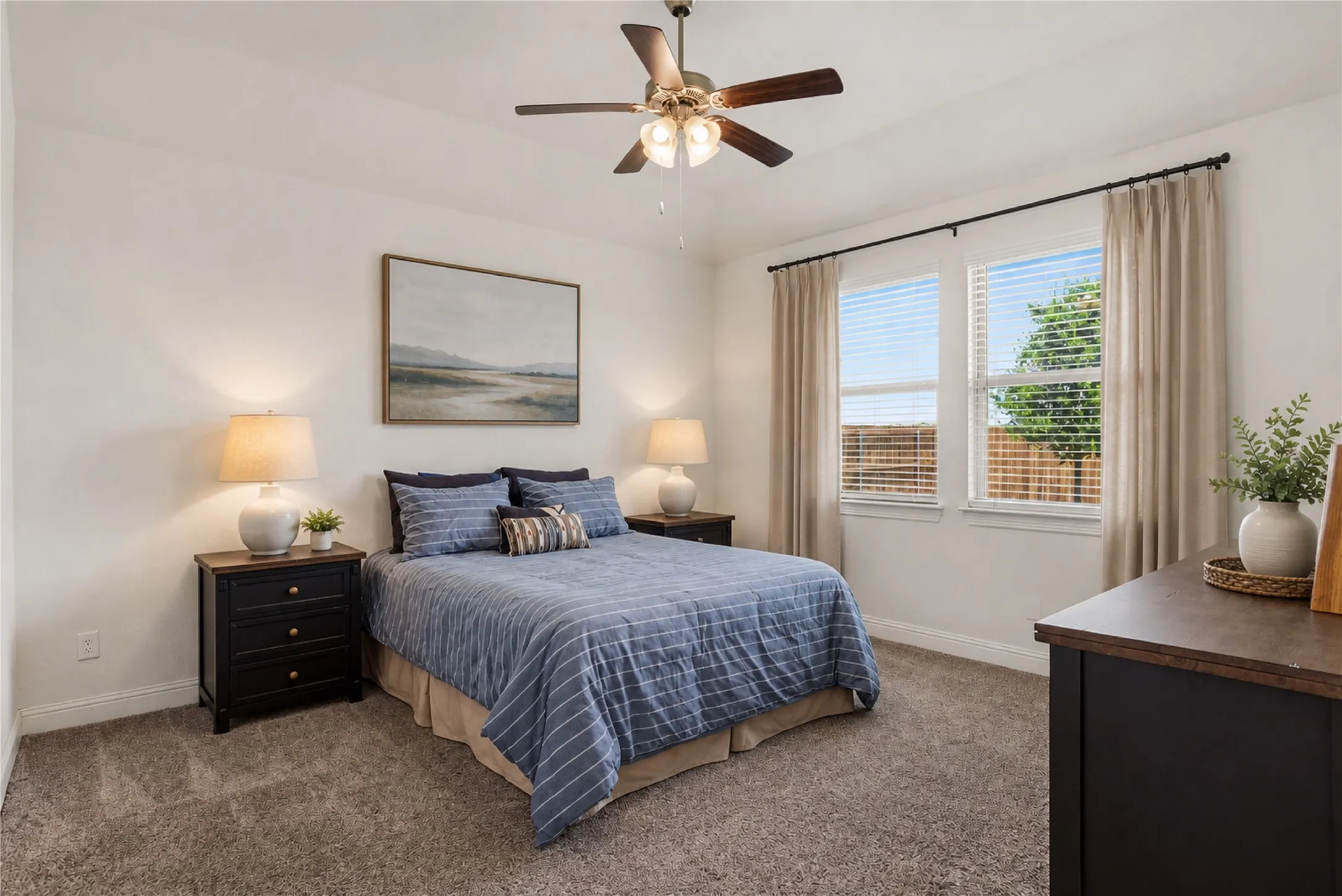 Bedroom featuring carpet flooring, two windows with blinds, and a ceiling fan with integrated lighting