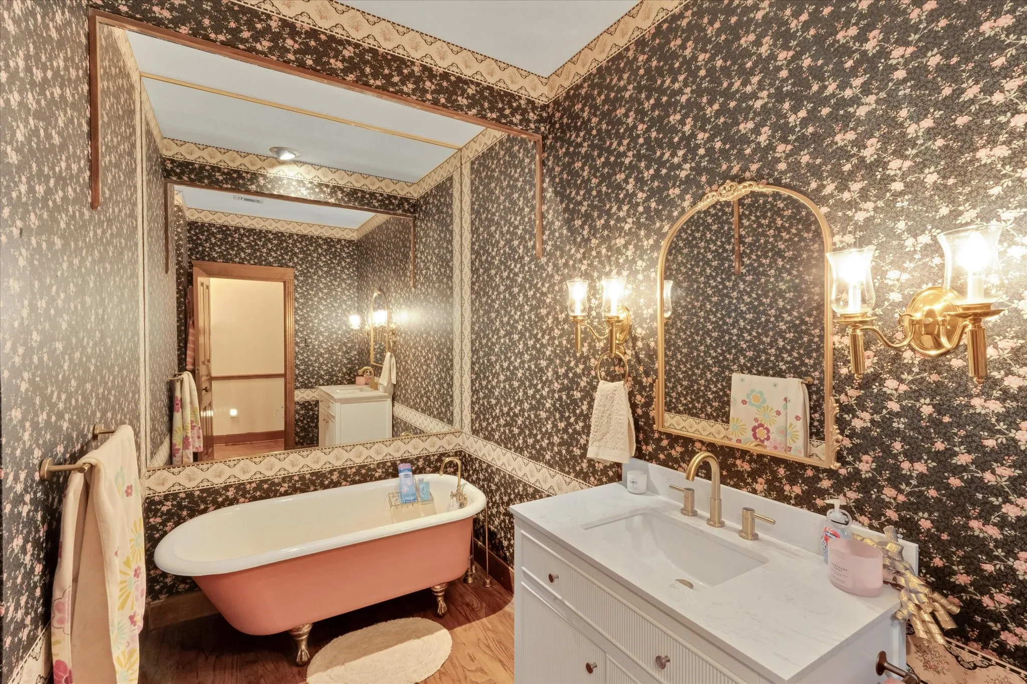 Vanity area featuring a built-in sink with a white countertop, gold-tone faucet, and an ornate arched mirror flanked by sconce lighting