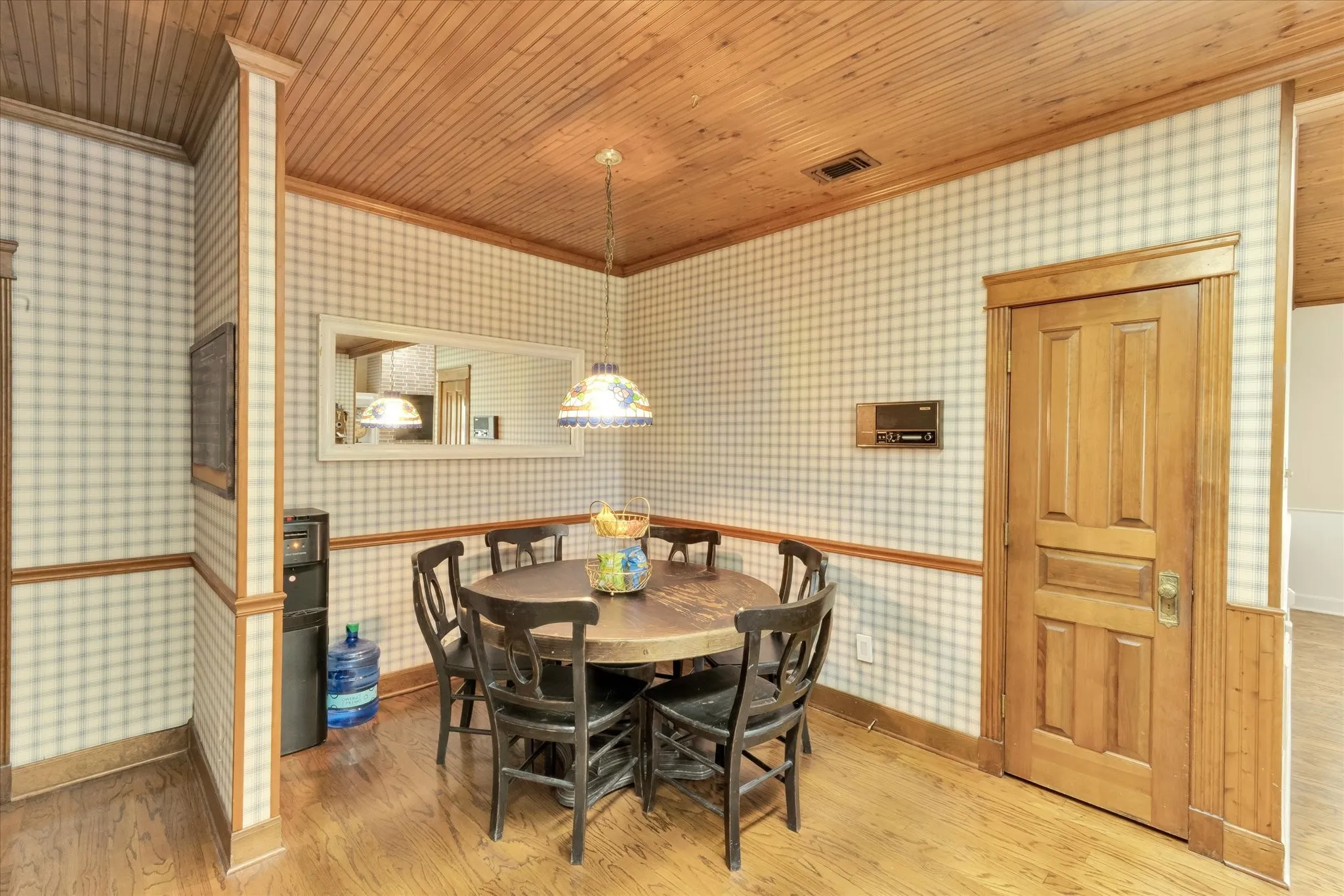Dining area featuring wood-finish flooring, wood paneling on the ceiling, and plaid pattern wallpaper