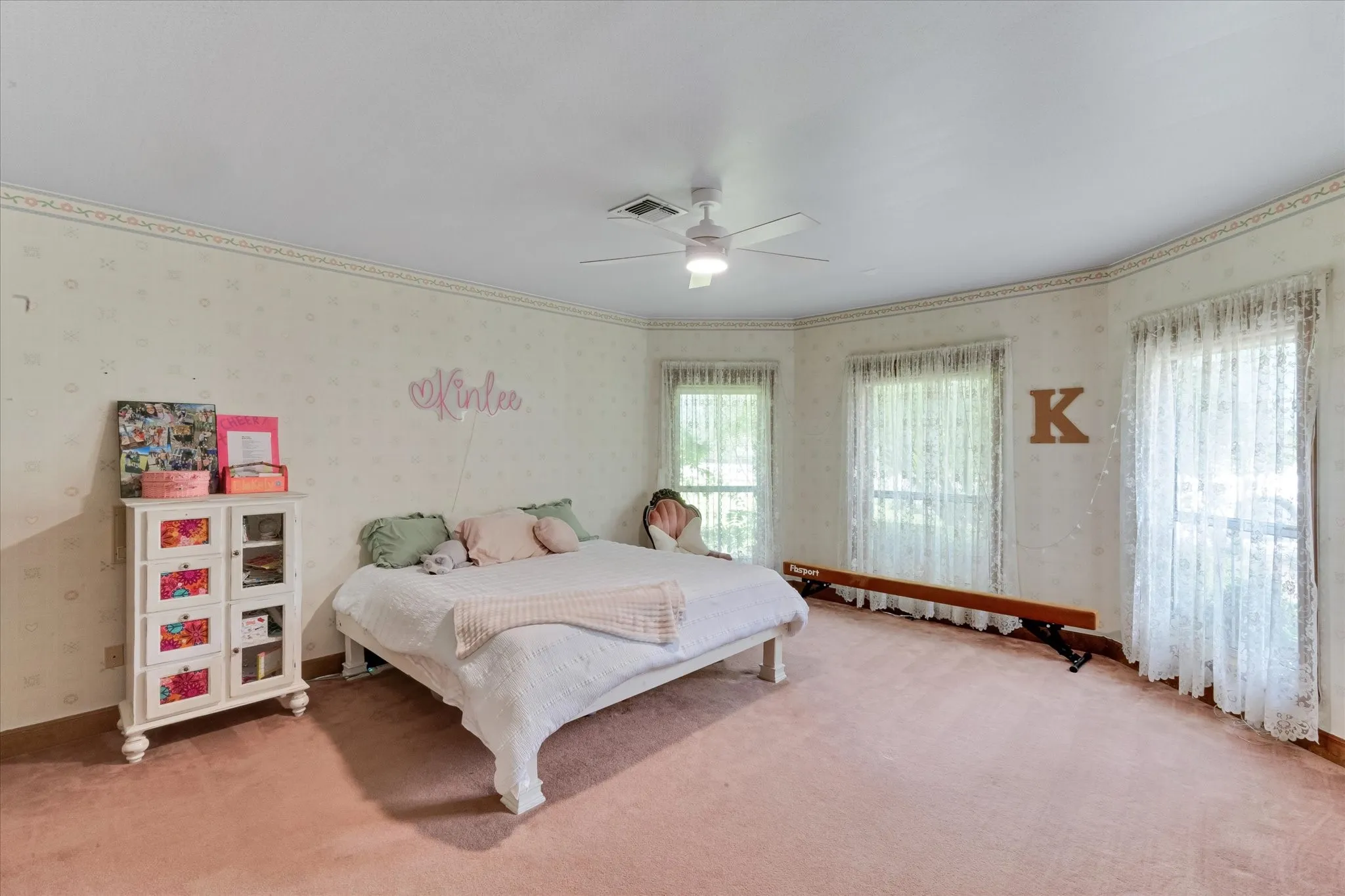 Spacious room featuring multiple windows, patterned wallpaper, a ceiling fan, and plush carpeting