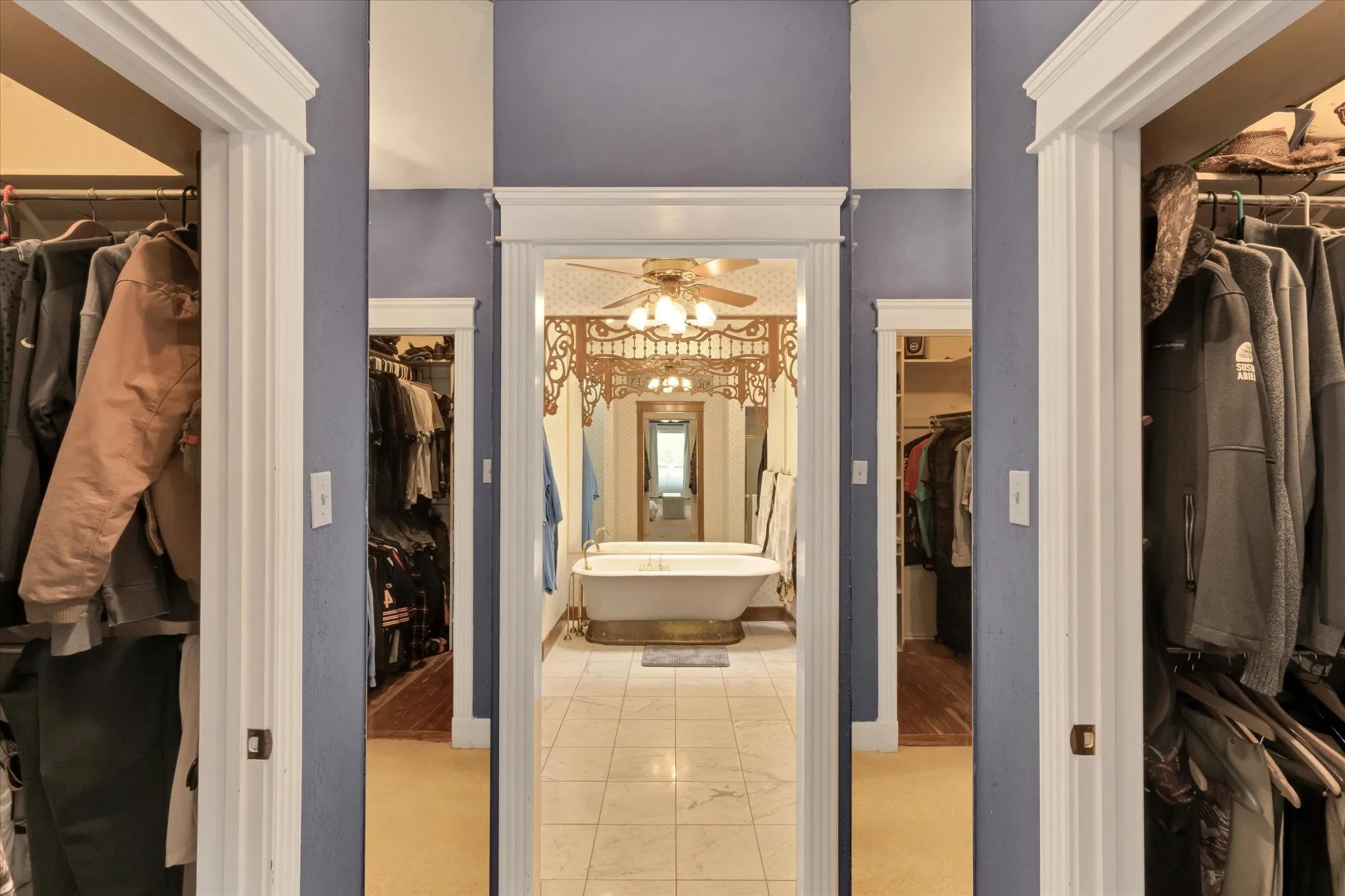 Spacious bathroom featuring a freestanding soaking tub, classic ceiling fan, and decorative architectural trim, enrty into primary bathroom