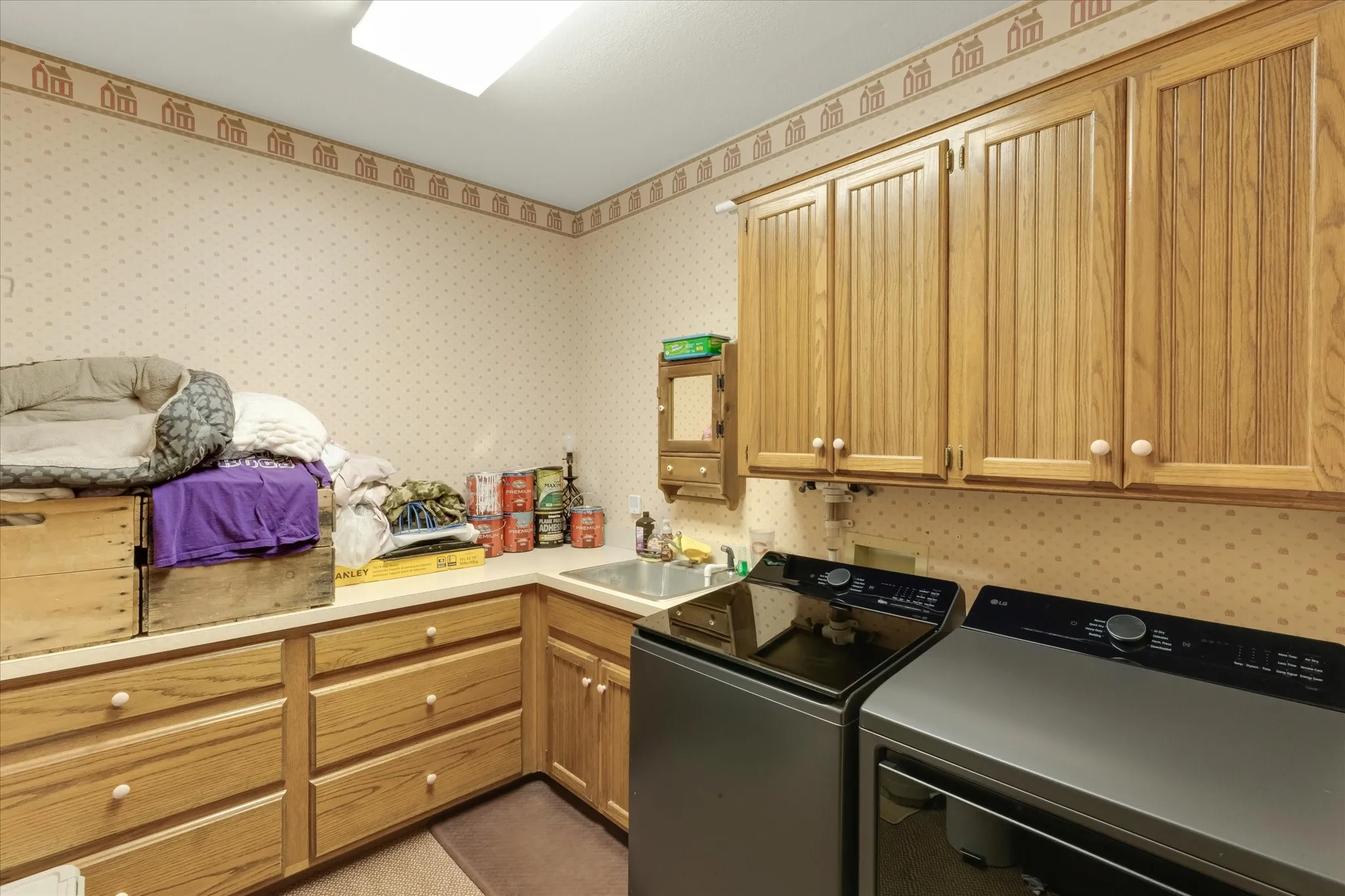 Utility room featuring extensive wood cabinetry, a built-in sink with a countertop, and a ceiling-mounted light fixture