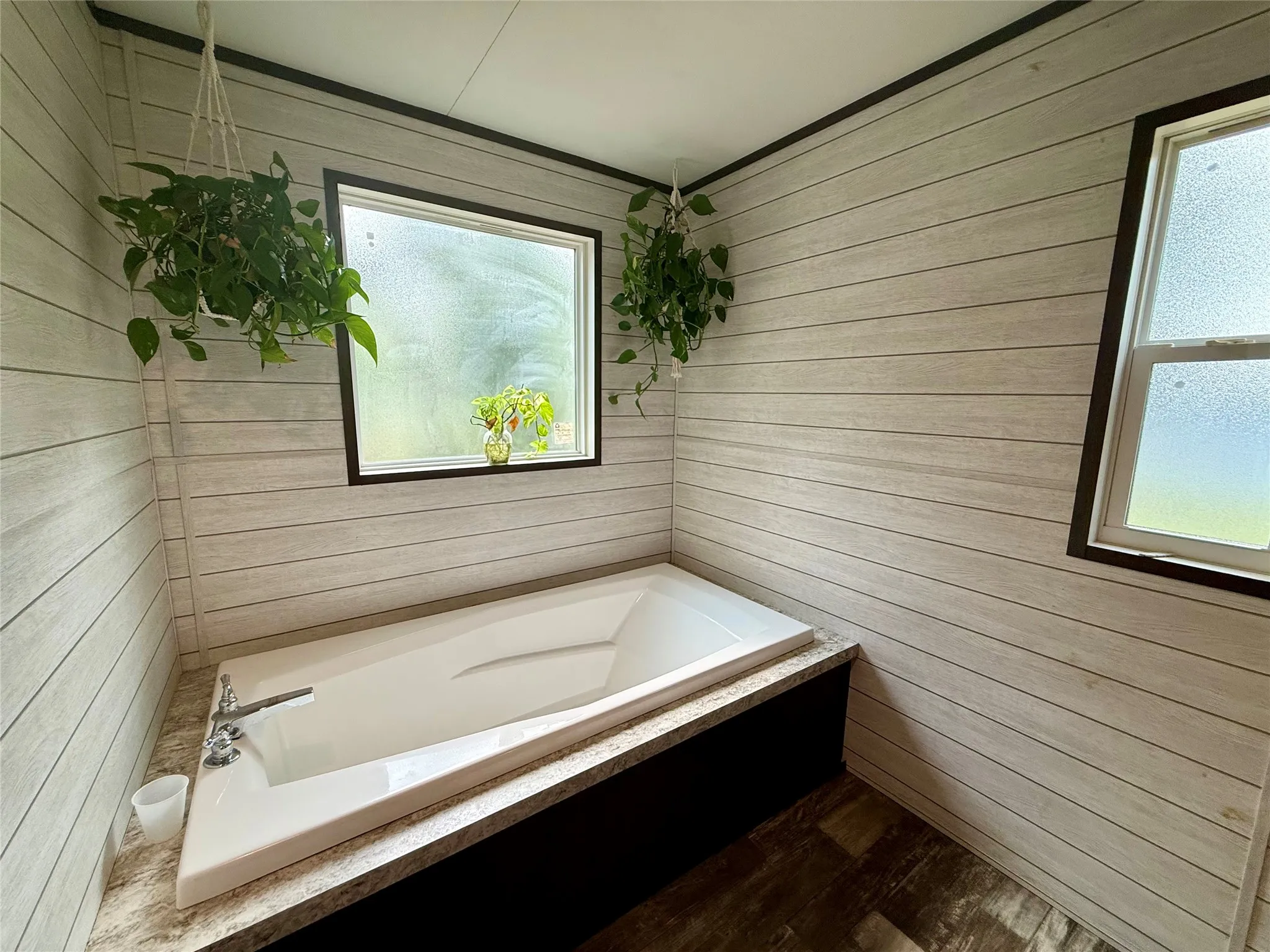 Built-in soaking tub with chrome fixtures, set against plank-style wall paneling