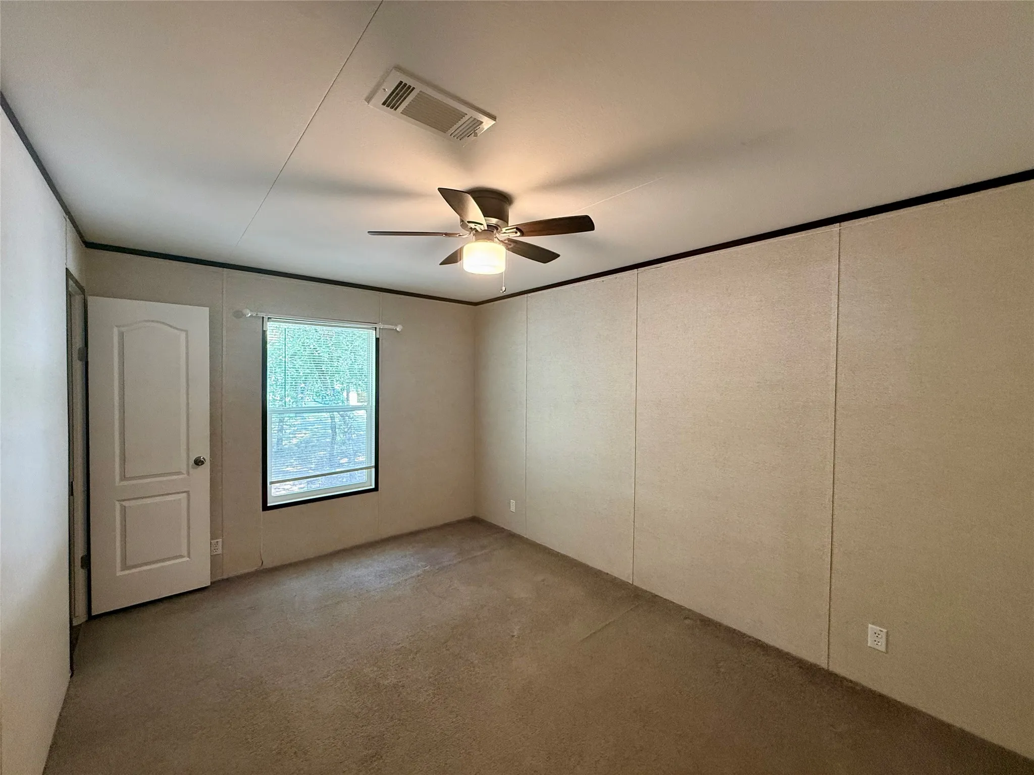 Carpeted room featuring a ceiling fan with integrated lighting, a paneled door, and a single window