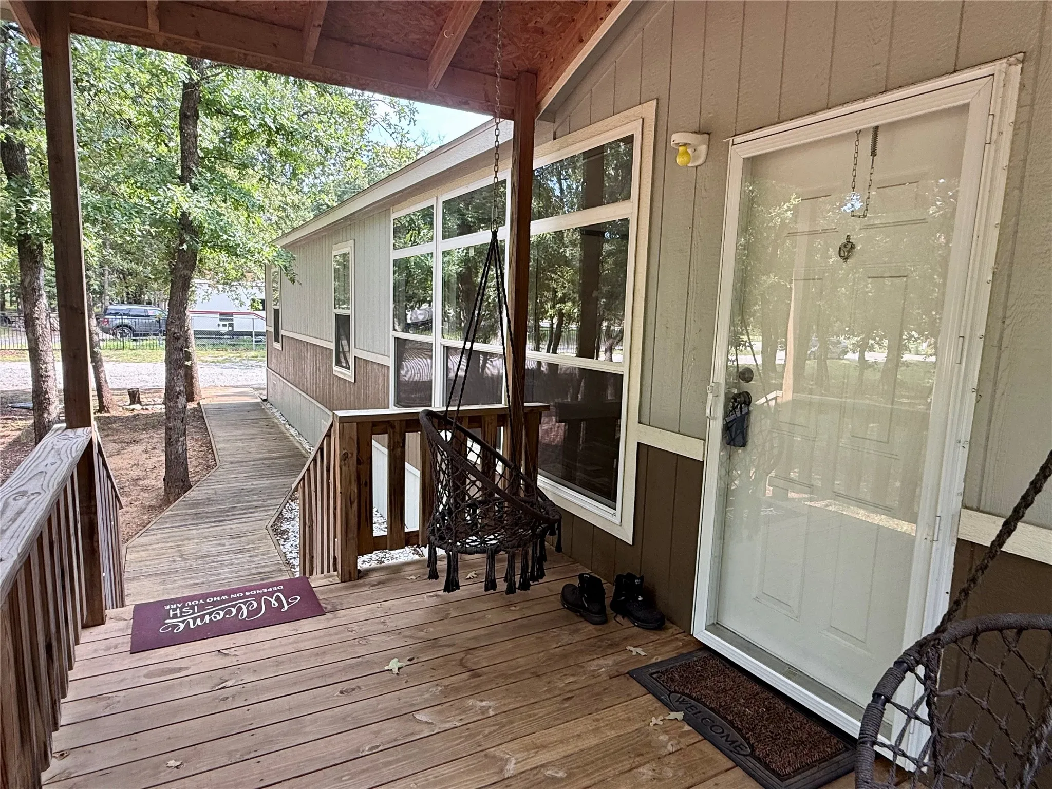 Expansive wood-finish deck with a built-in ramp, white entry door, and large windows