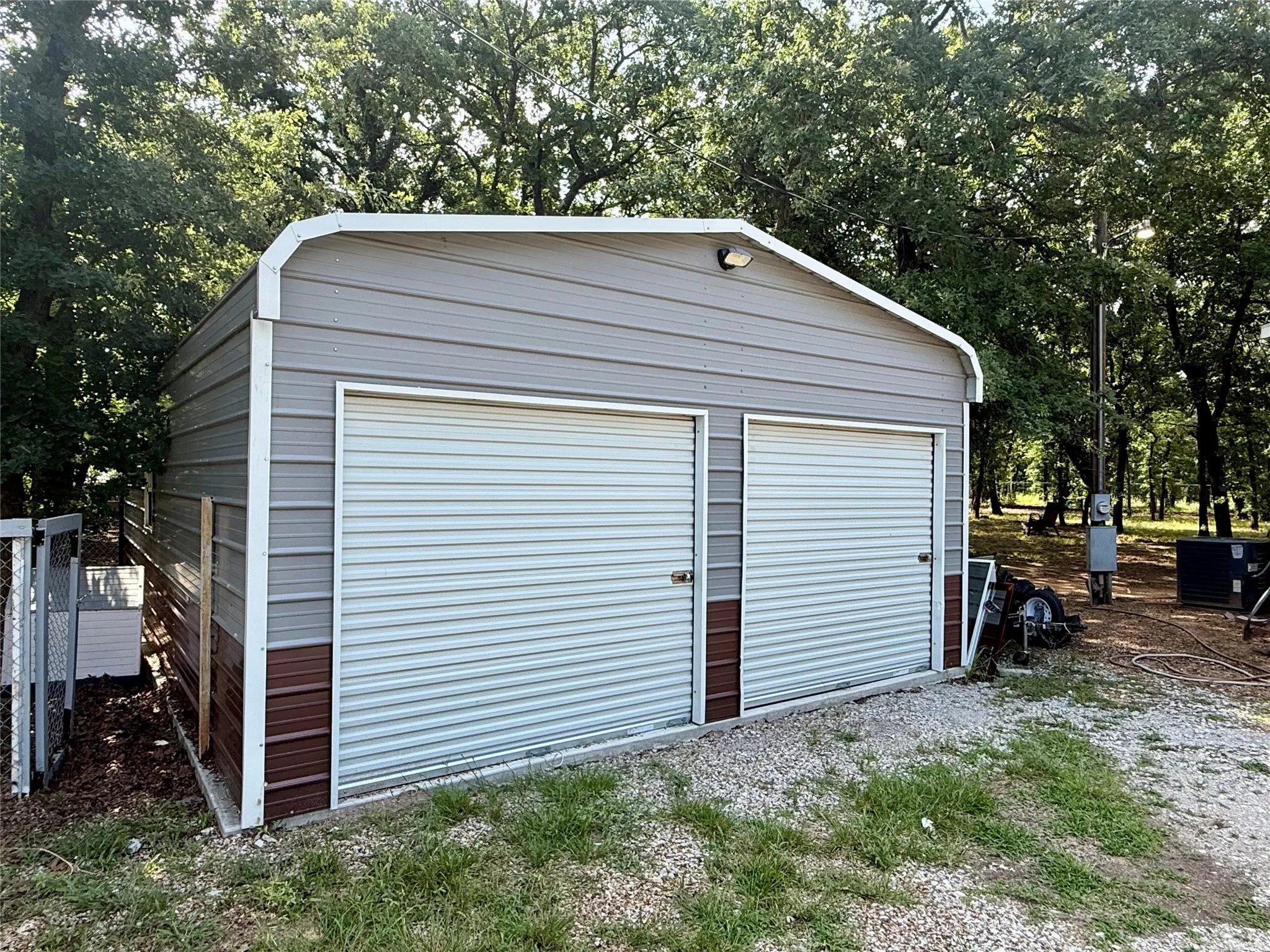 Two-bay metal outbuilding with corrugated siding and two roll-up doors, set on a concrete slab