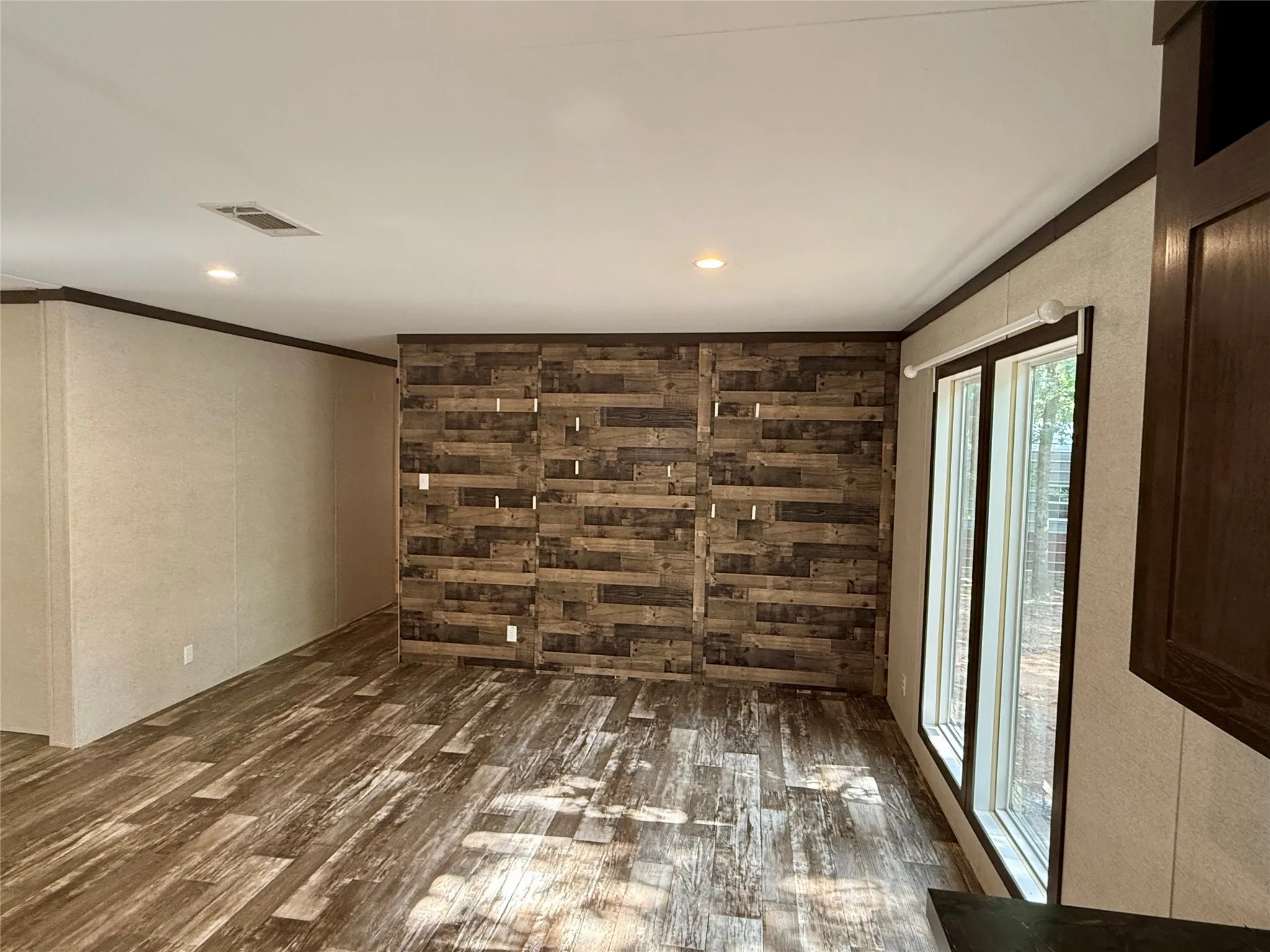 Interior space featuring a decorative wood-panel accent wall, wood-finish flooring, recessed lighting, and large windows