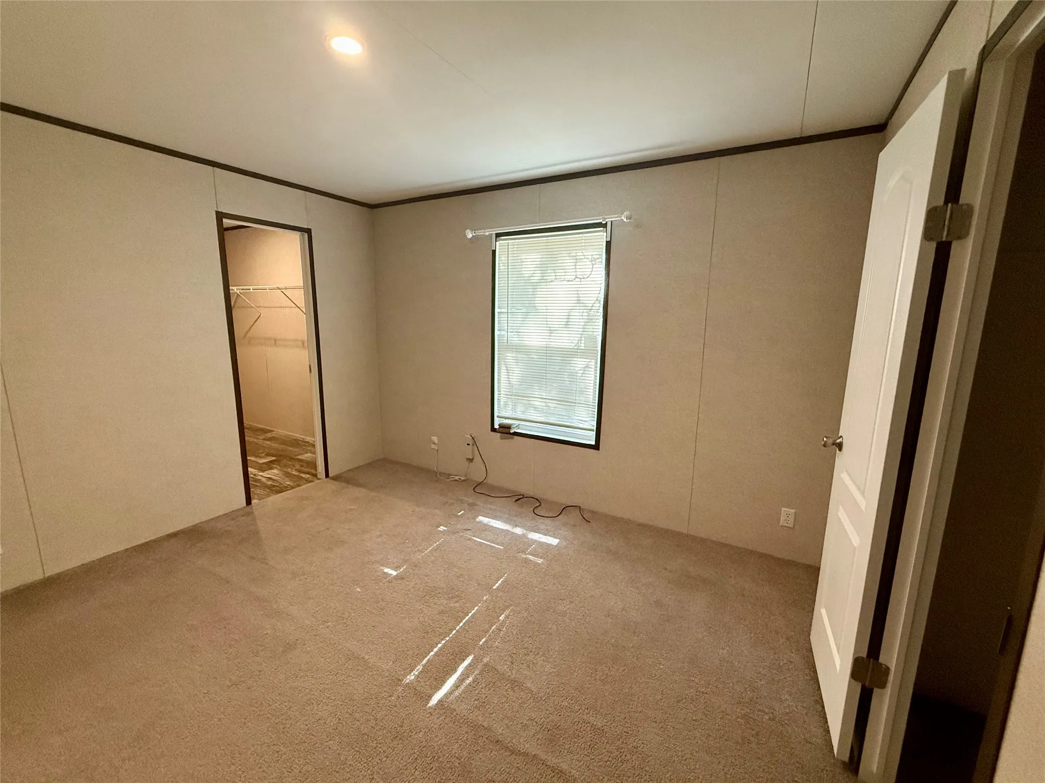 Carpeted room with a single window, overhead recessed lighting, and a closet featuring wire shelving and wood-finish flooring