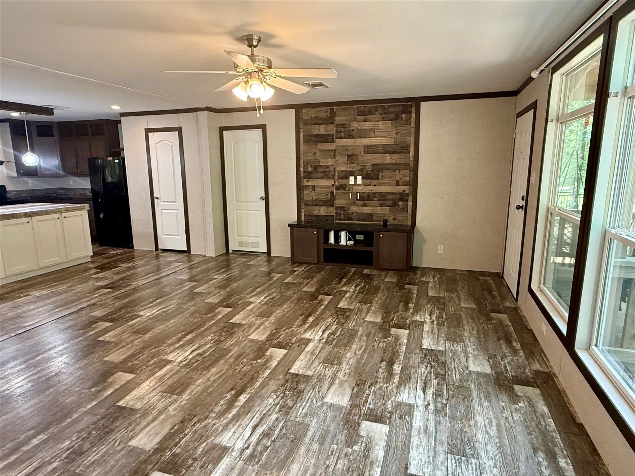 Spacious living area featuring wood-finish flooring and a ceiling fan