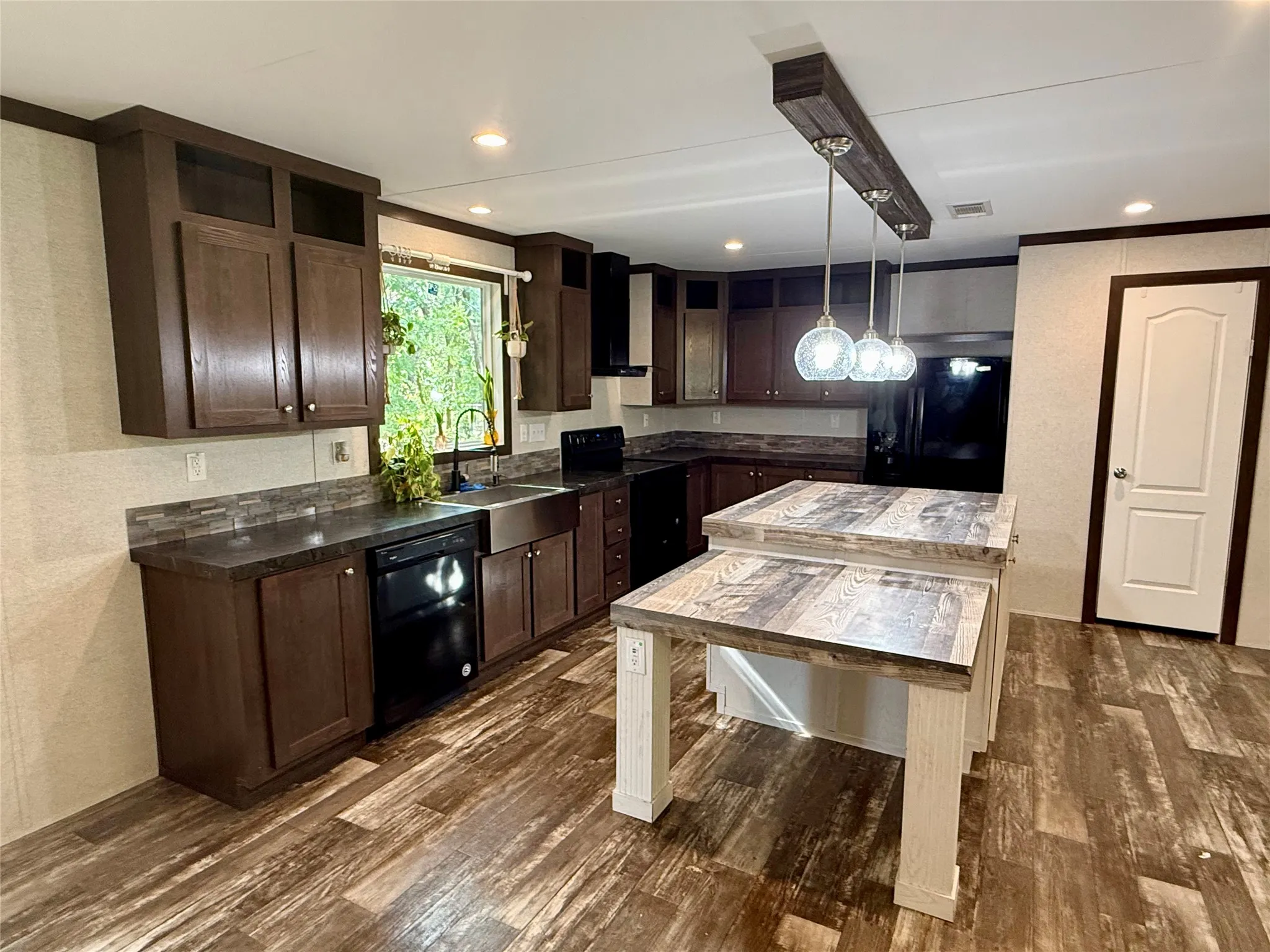 Modern kitchen featuring a two-tiered island with wood-finish countertop, dark wood cabinetry, and wood-finish flooring