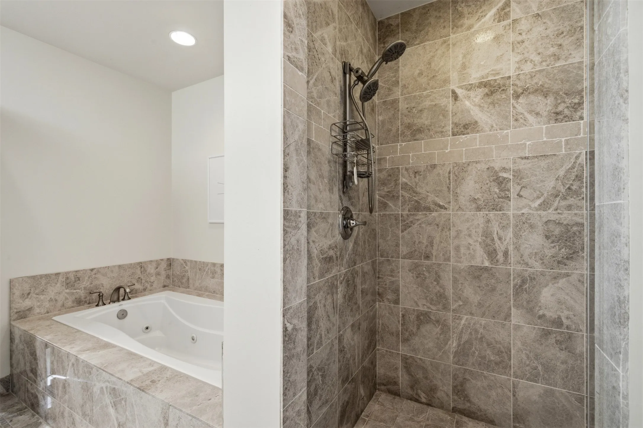 Separate Shower in primary Bath with enclosure featuring large format stone-finish tile, accented by a horizontal subway tile band, and equipped with a dual shower head system