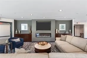 Tower Party Room Recessed lighting illuminates this inviting common area, featuring an integrated linear fireplace and a wall-mounted display