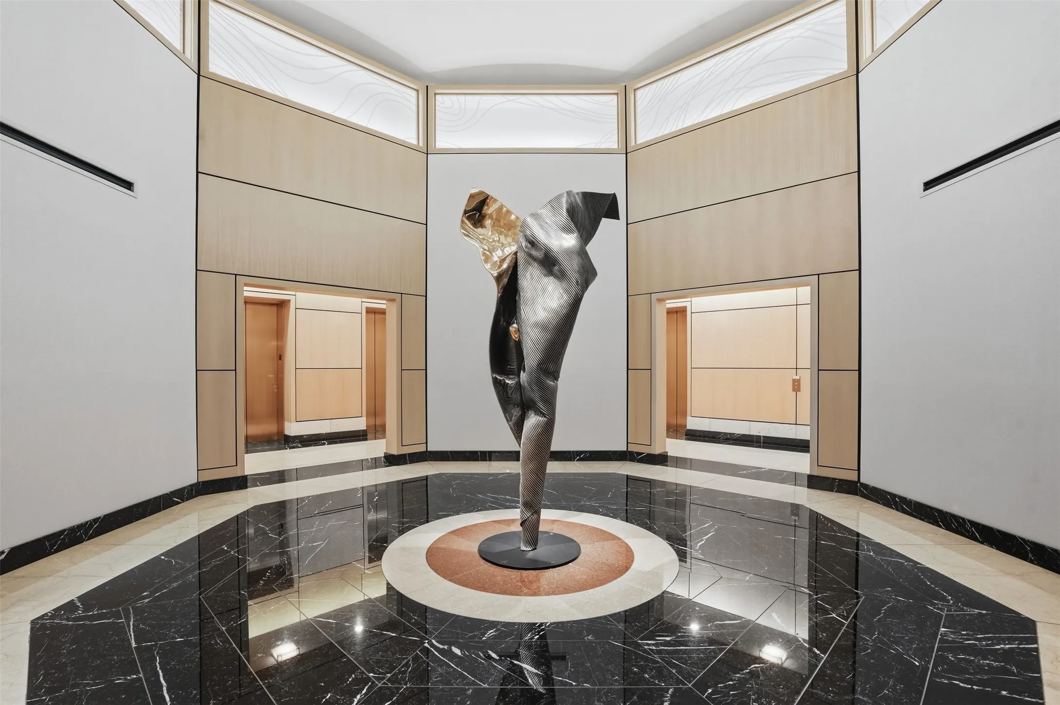 Grand foyer featuring a geometric black marble floor with white veining Art sculpture that depicts the Tornado of 2001 that hit the Tower when it wa the Bank One office building prior to the creation of the Tower Residential Condos, light wood paneling, and frosted glass transom windows accent the foyer