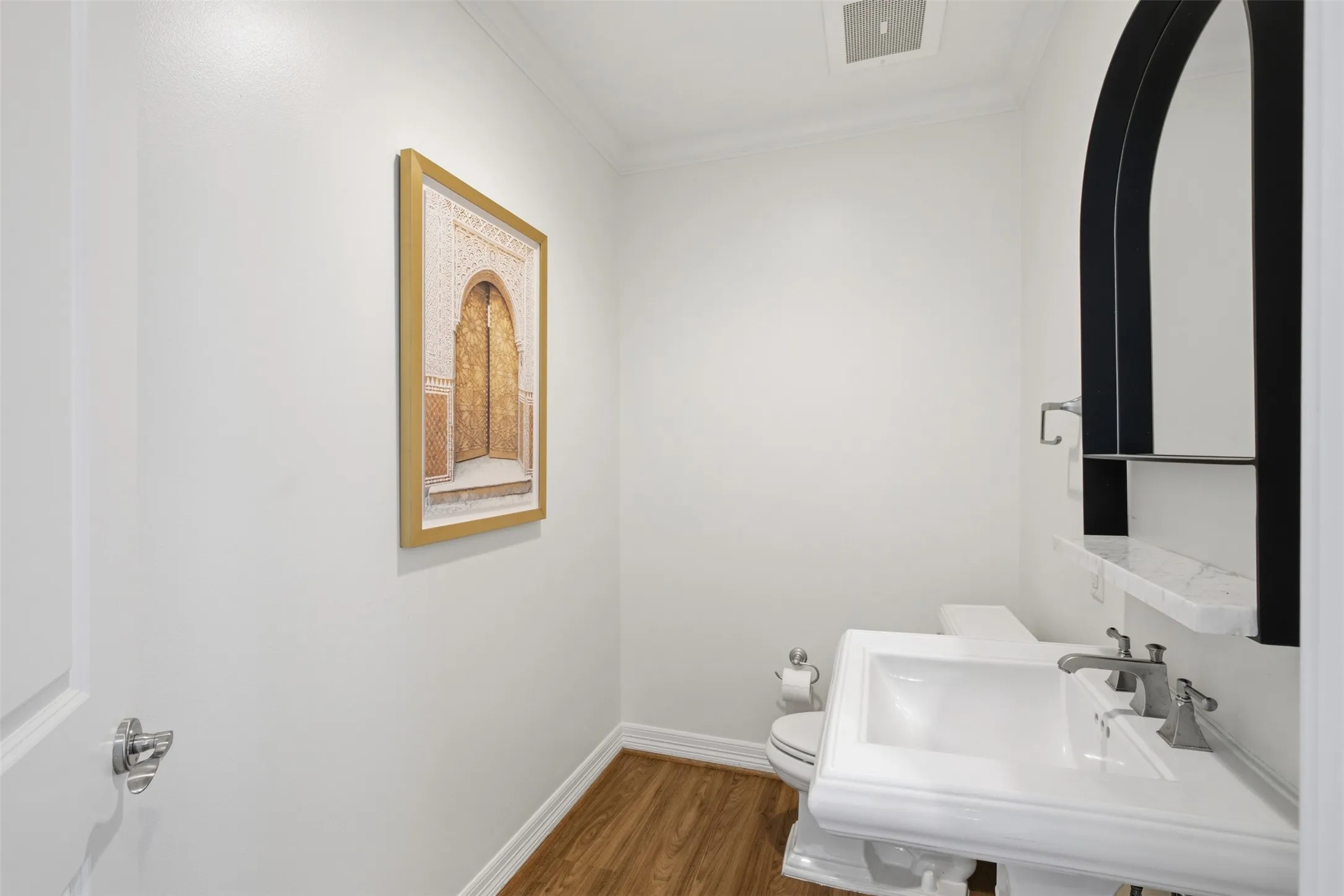 Guest half bath Powder room featuring a white pedestal sink with a dual-handle faucet, a toilet, and wood-finish flooring