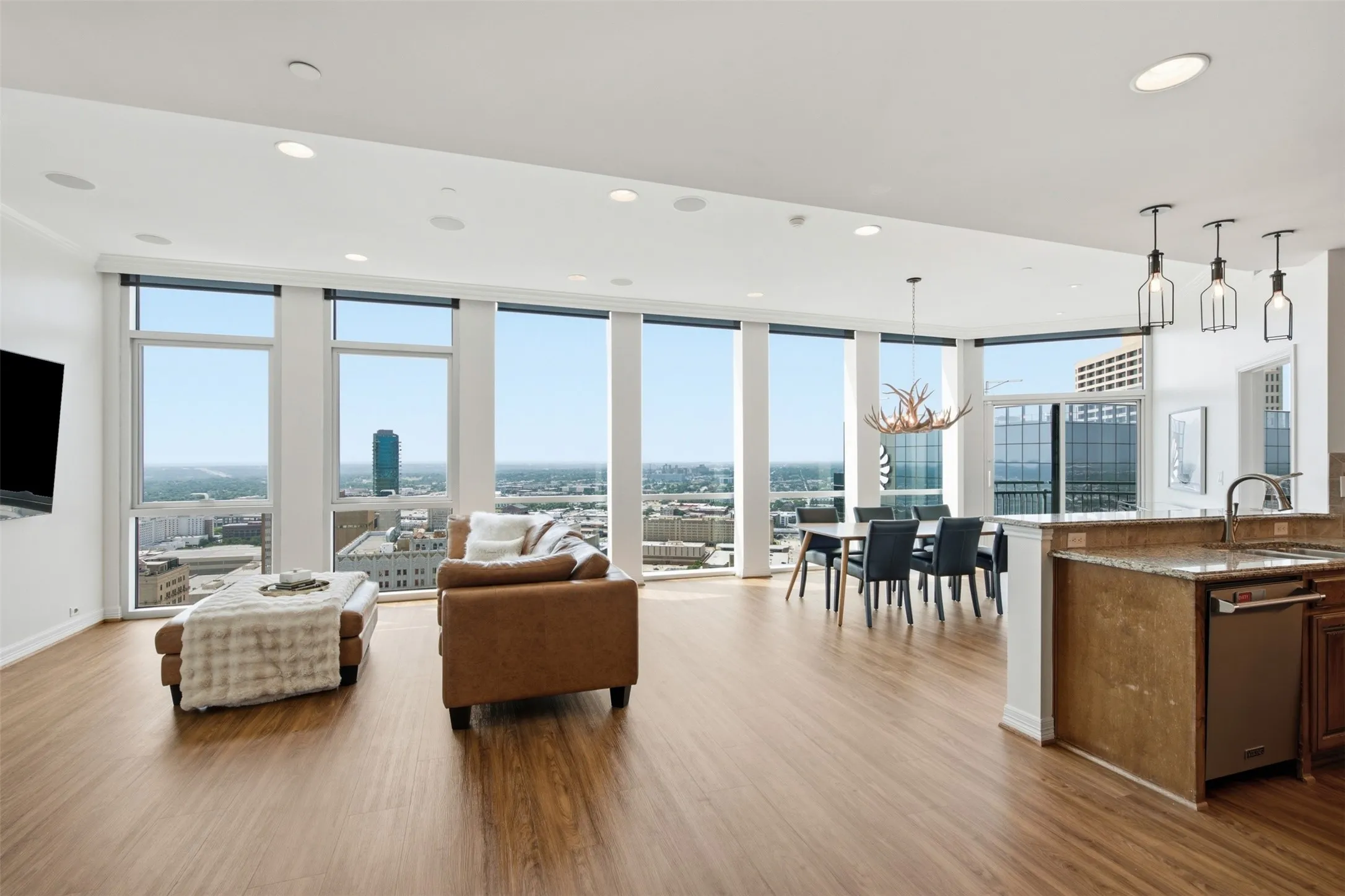 Walls of Windows with open horizon views of the city!  Open-concept living space featuring floor-to-ceiling windows, wood-finish flooring, recessed lighting, and a kitchen island with stone countertop