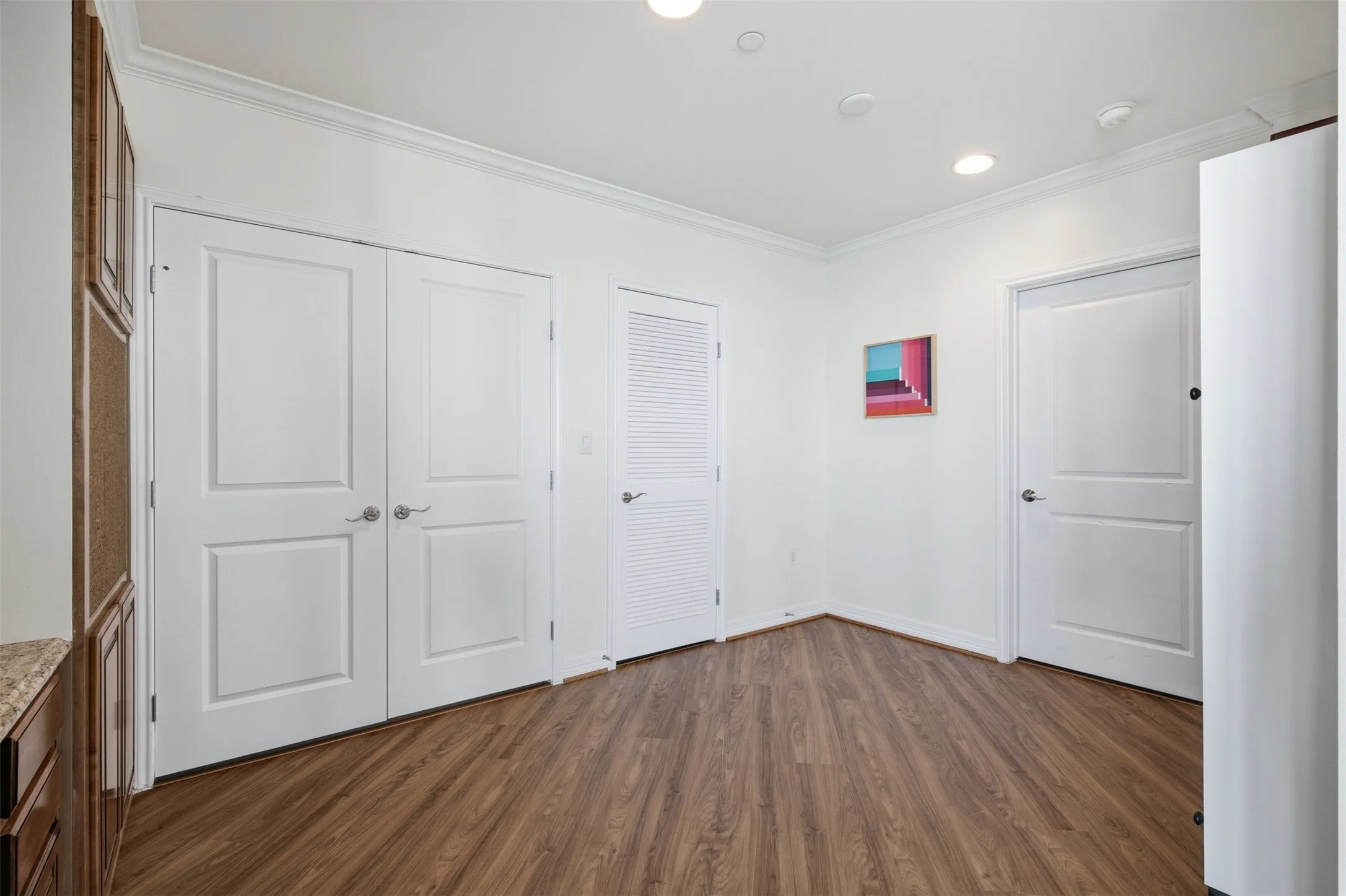 Room featuring luxury vinyl plank wood-finish flooring, white walls, and crown molding  This room open into the 8 x24 Bonus Area (not pictured) that is a great storage, media room or flex space for your lifestyle!
