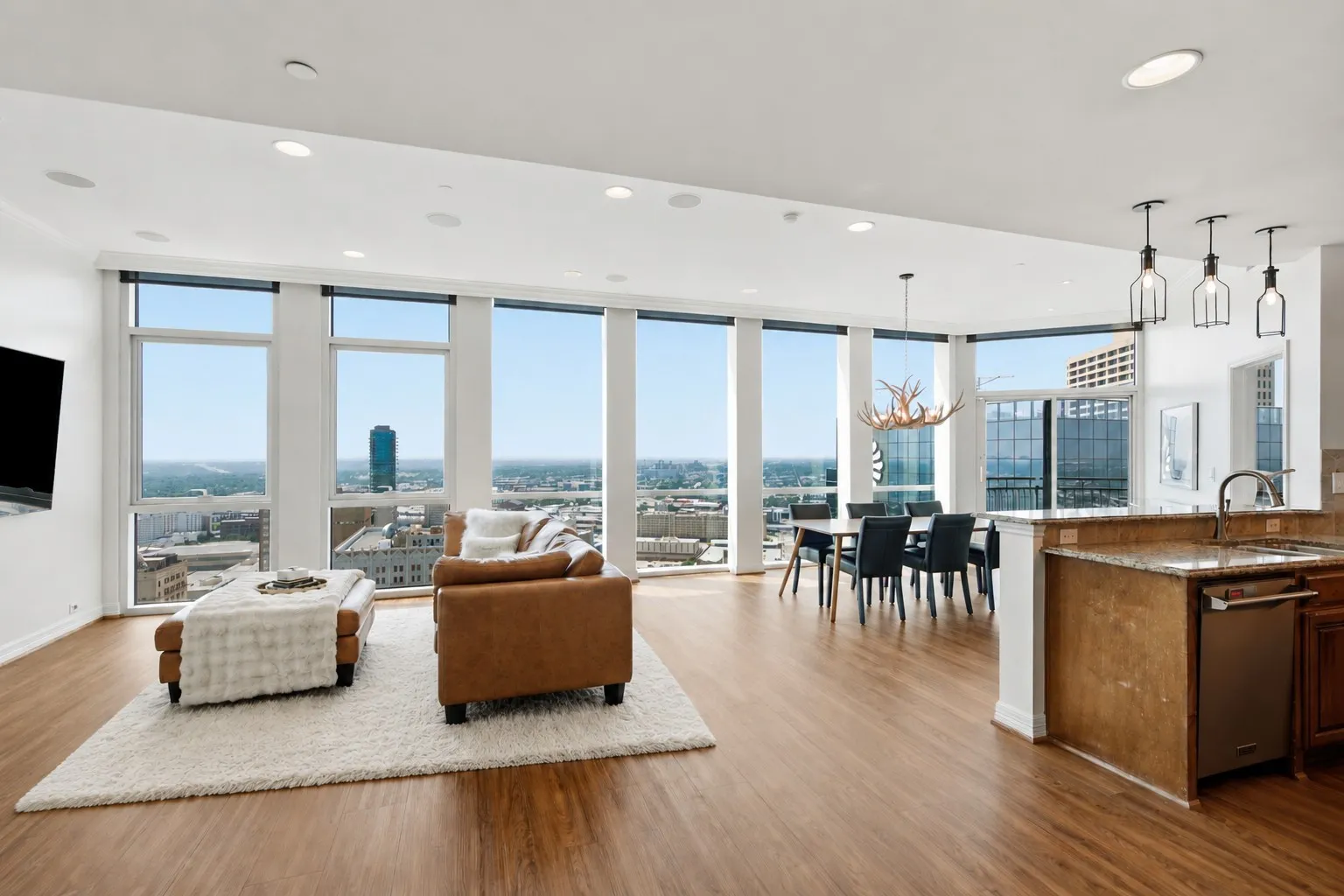 Open-concept living space featuring floor to ceiling windows, wood-finish flooring, a kitchen island with stone countertop, and recessed ceiling lighting