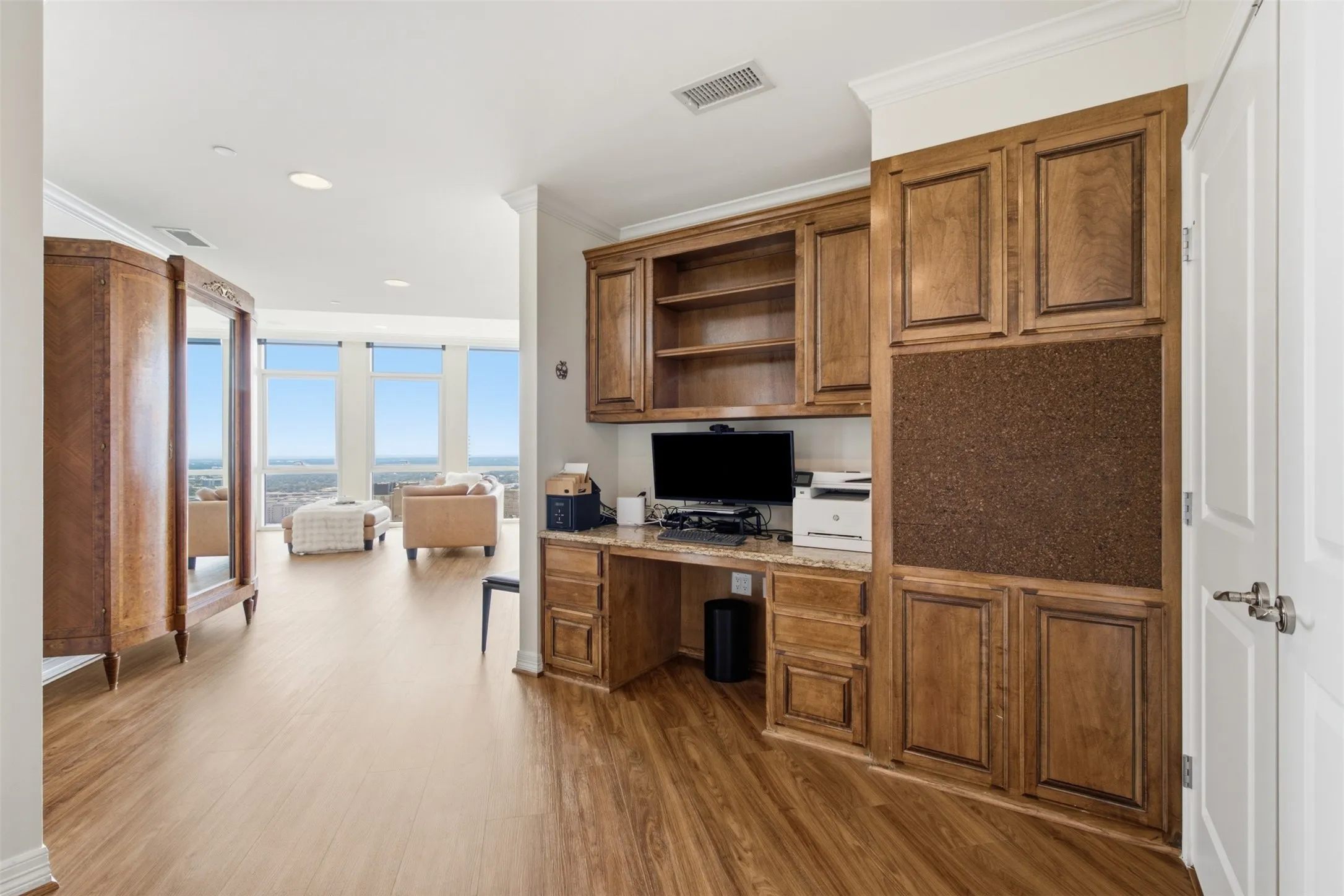 Integrated custom wood-finish cabinetry with built-in desk, shelving, and cork board is the perfect space for your downtown office in the central business district of Downtown Fort Worth!