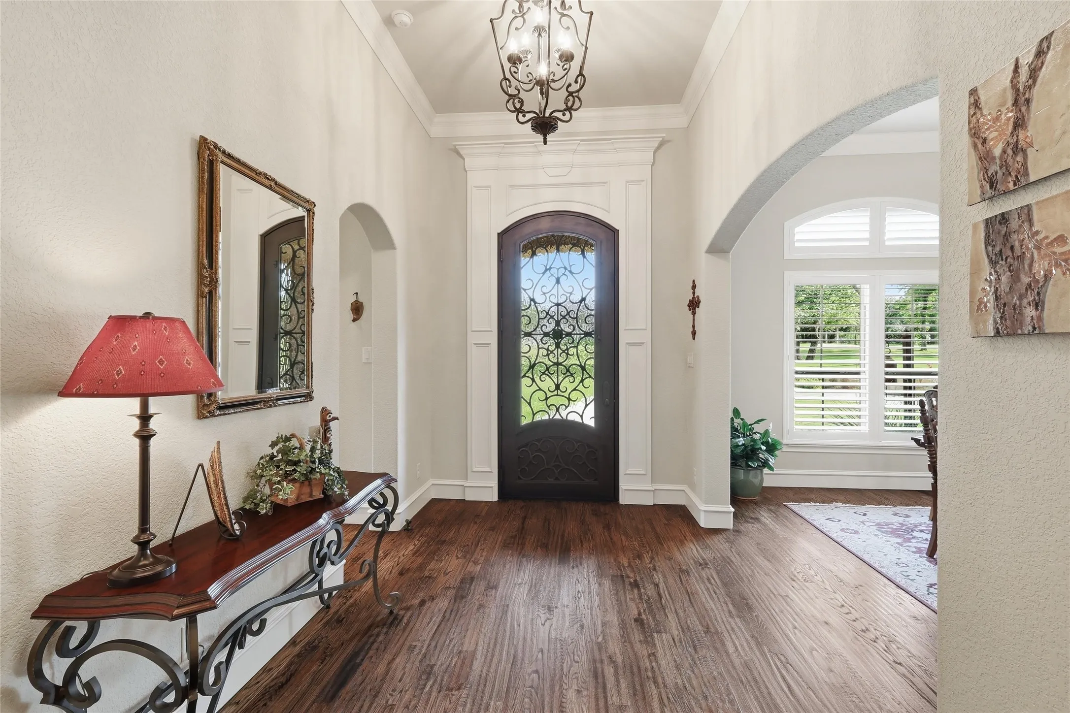 Grand entryway featuring rich wood-finish flooring and a decorative front door with iron scrollwork
