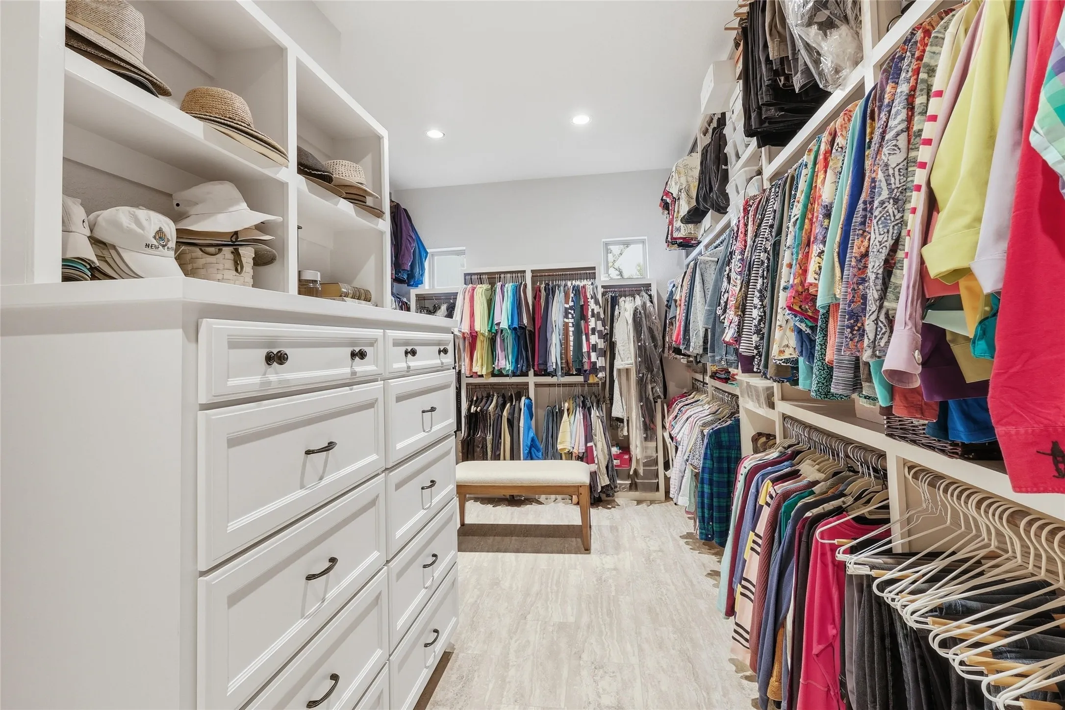 Custom closet system featuring extensive built-in cabinetry with drawers, open shelving, multiple hanging rods