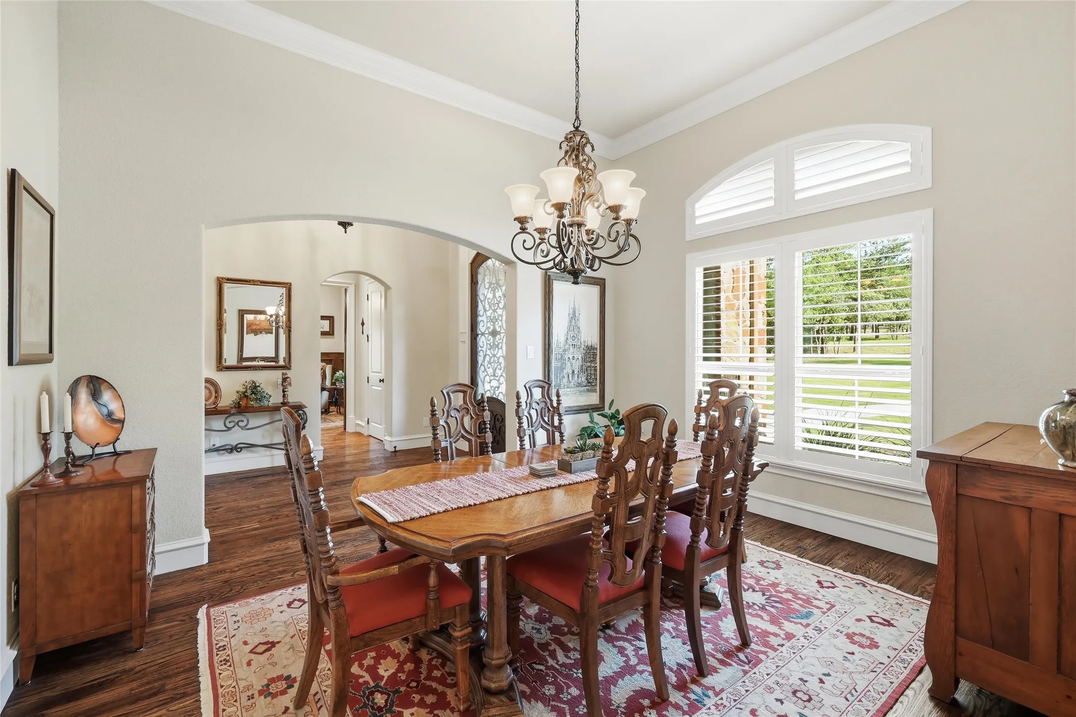 Dining space featuring wood-finish flooring, an arched entryway, and a chandelier
