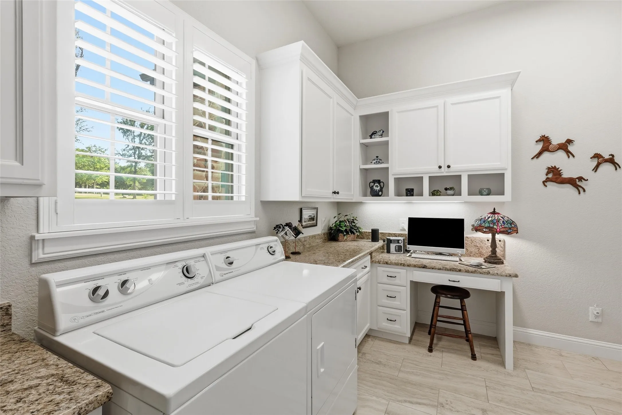 Functional utility room featuring white cabinetry, light-toned wood-finish flooring, and granite-style countertops
