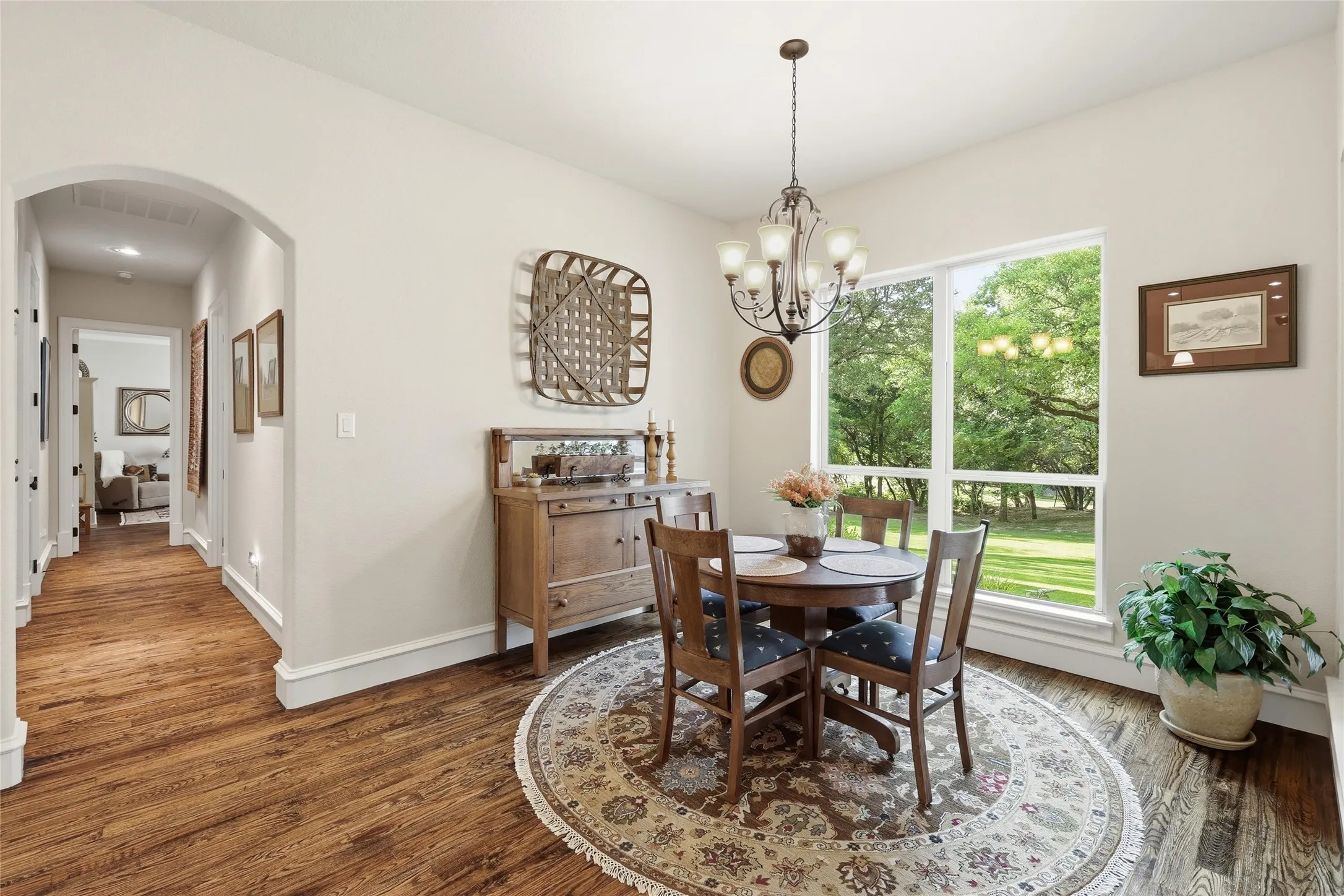Dining space featuring wood-finish flooring, a large window, and an arched entryway