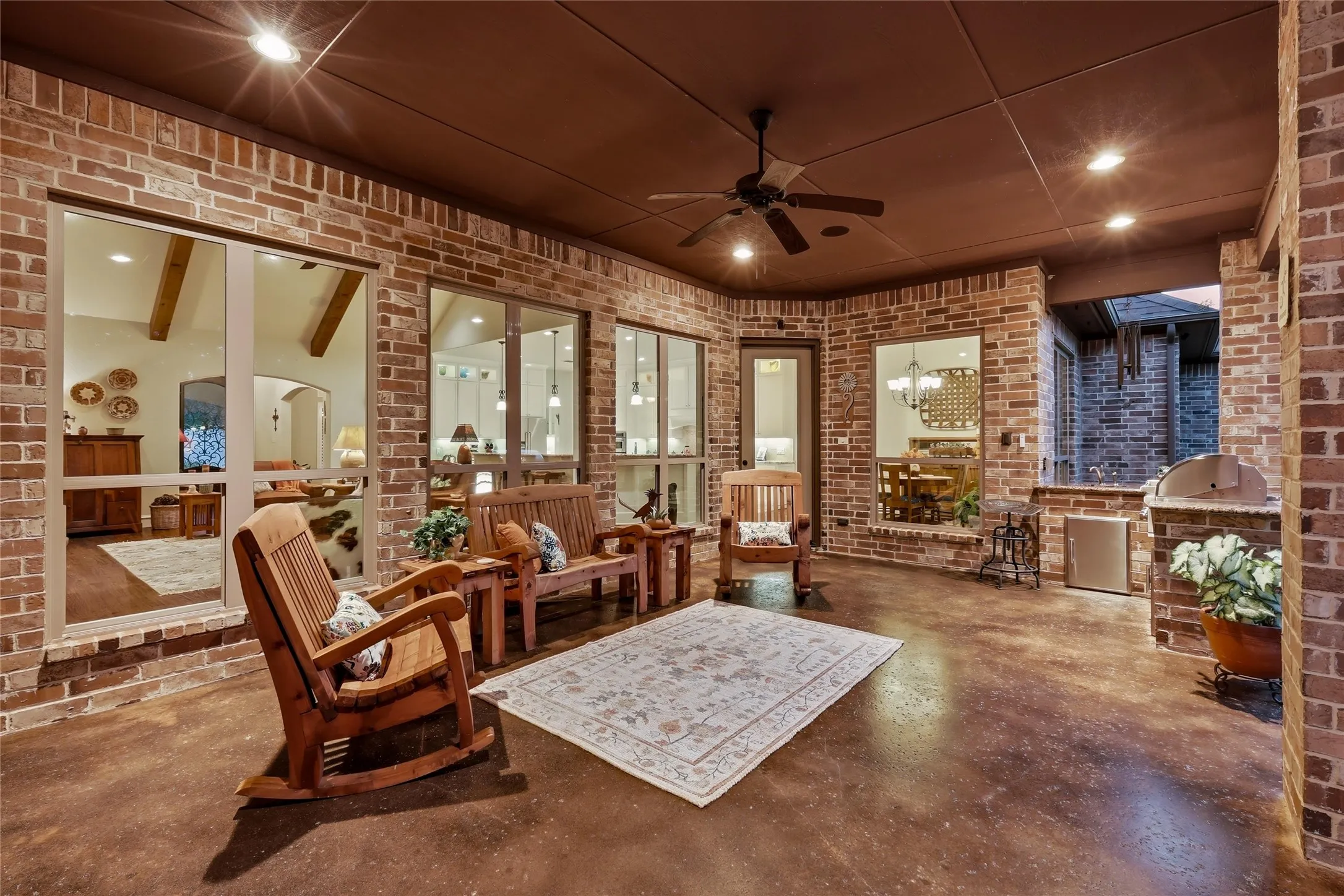 Covered patio featuring a brick exterior, recessed lighting, ceiling fan, and a built-in outdoor kitchen with a grill and stainless steel refrigerator