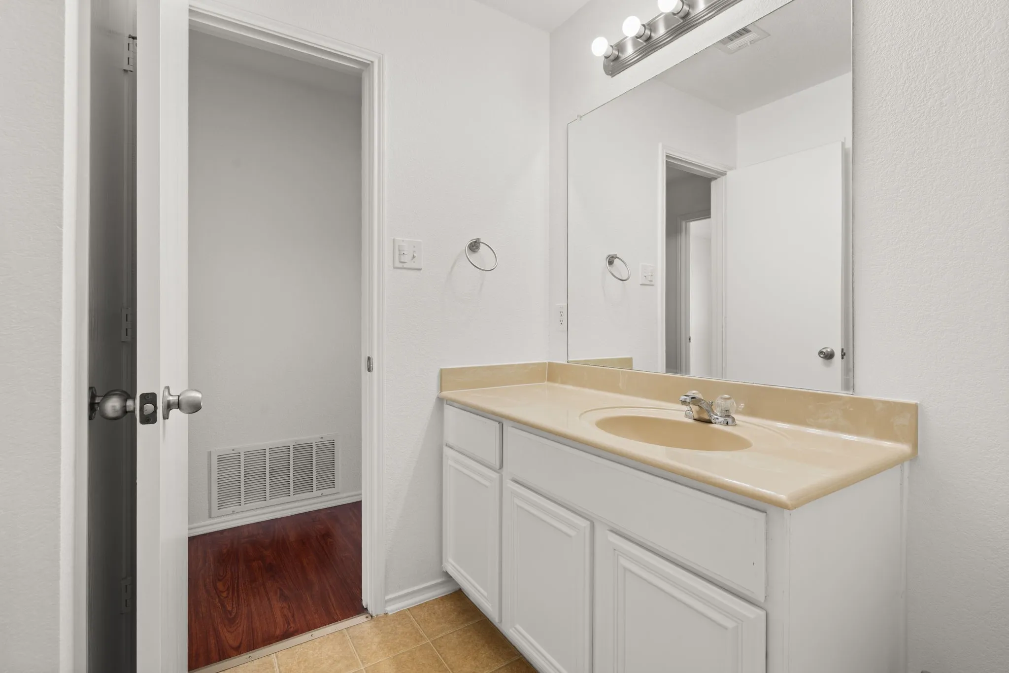 White vanity with dual cabinet doors and an integrated beige countertop sink