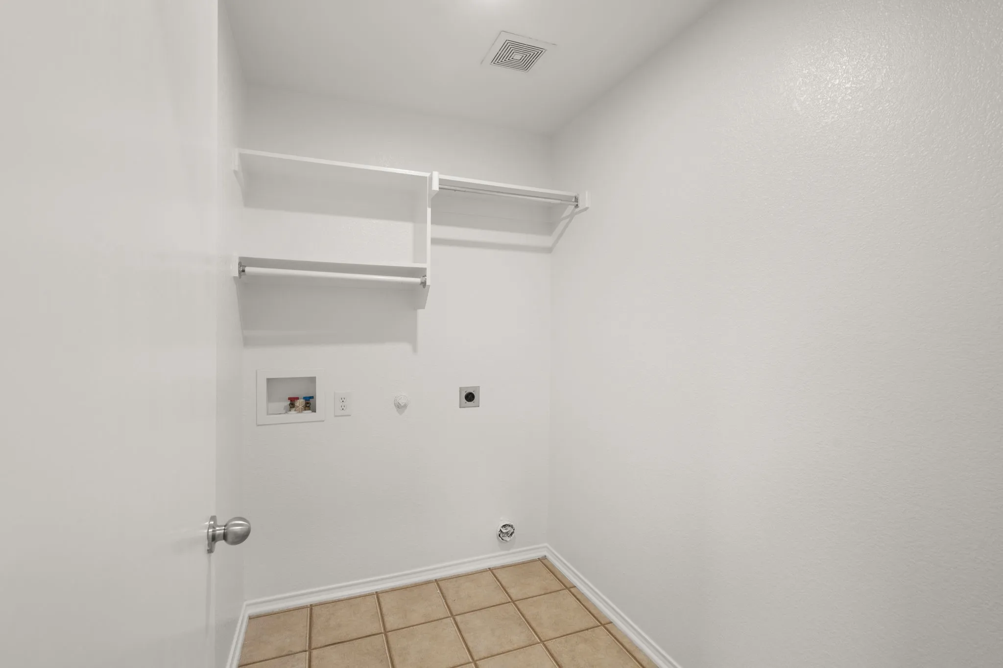 Utility room featuring integrated shelving, clothes hanging bar, and tile flooring