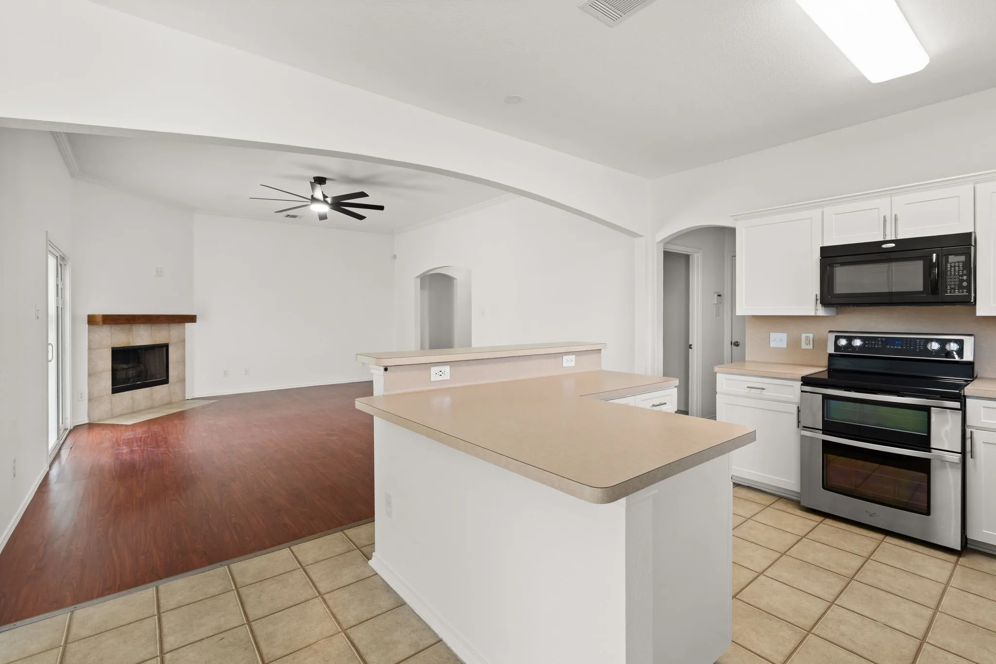 Kitchen featuring white cabinetry, light countertops, black microwave, stainless steel range, and tiled flooring